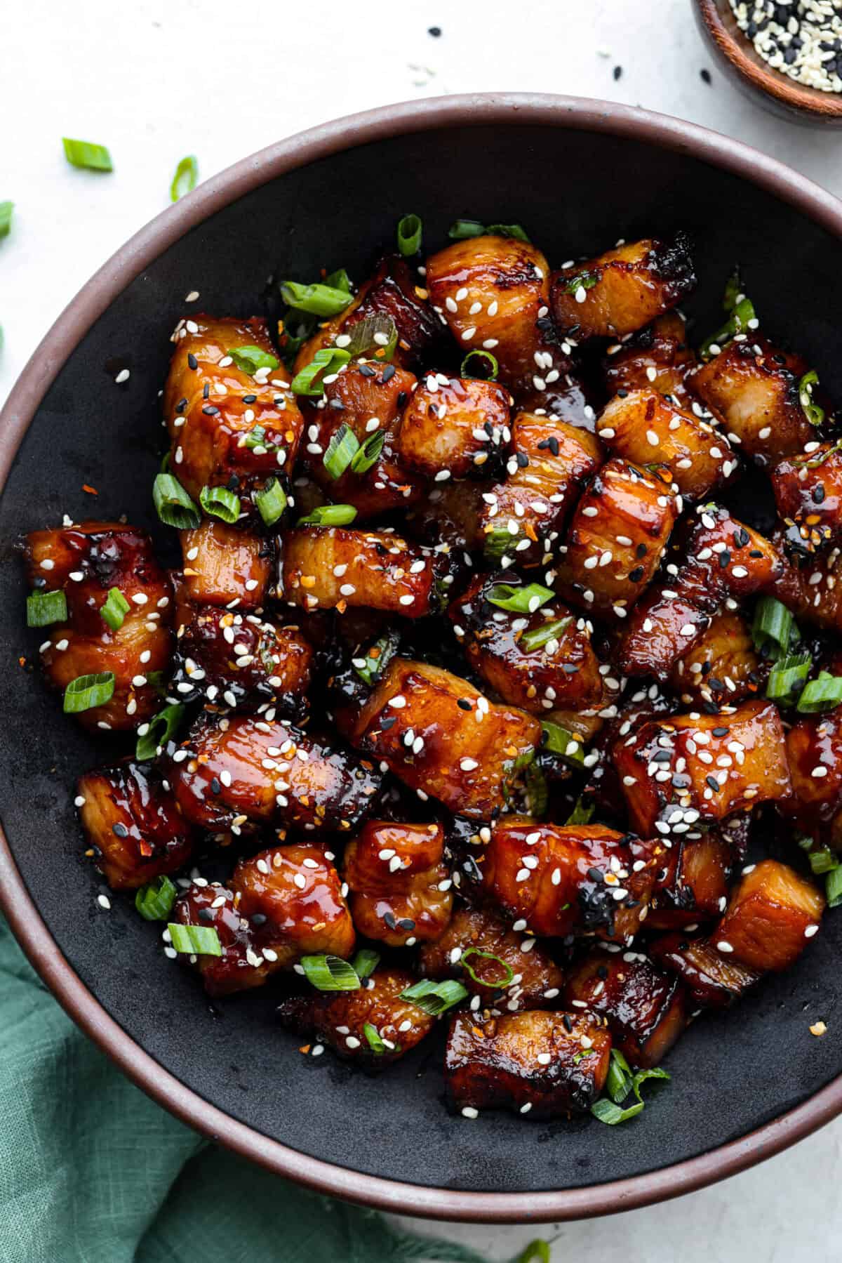 This simple air fryer pork belly recipe is great for making and enjoying this indulgent snack. It's meaty, crispy, smothered in a sticky, salty marinade that sets the flavors off perfectly! Overhead shot of plated air fryer pork belly.