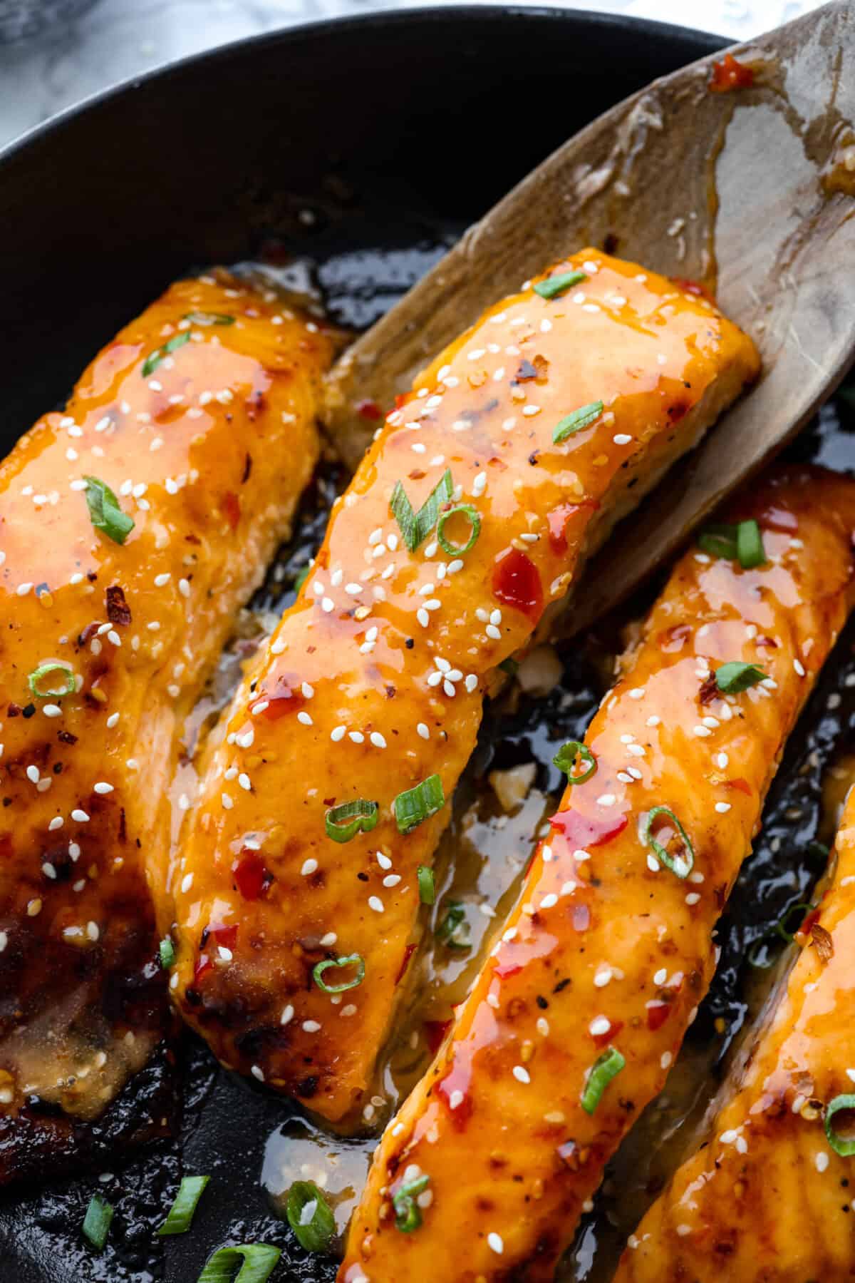 Bang Bang Salmon takes salmon filets, smothered in bang bang sauce, which is sweet with a kick, and then baked to perfection. You will love this simple yet oh-so-tasty dinner that can beย ready to serve in less than 30 minutes! Overhead shot of bang bang salmon in a skillet.