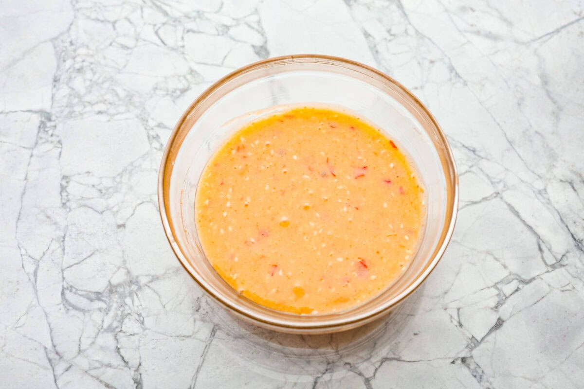 Bang Bang Salmon takes salmon filets, smothers them in bang bang sauce that is sweet with a kick, and then baked to perfection. You will love this simple yet oh-so-tasty dinner that can be ready to serve in less than 30 minutes! Overhead shot of mixed sauce ingredients in a bowl.