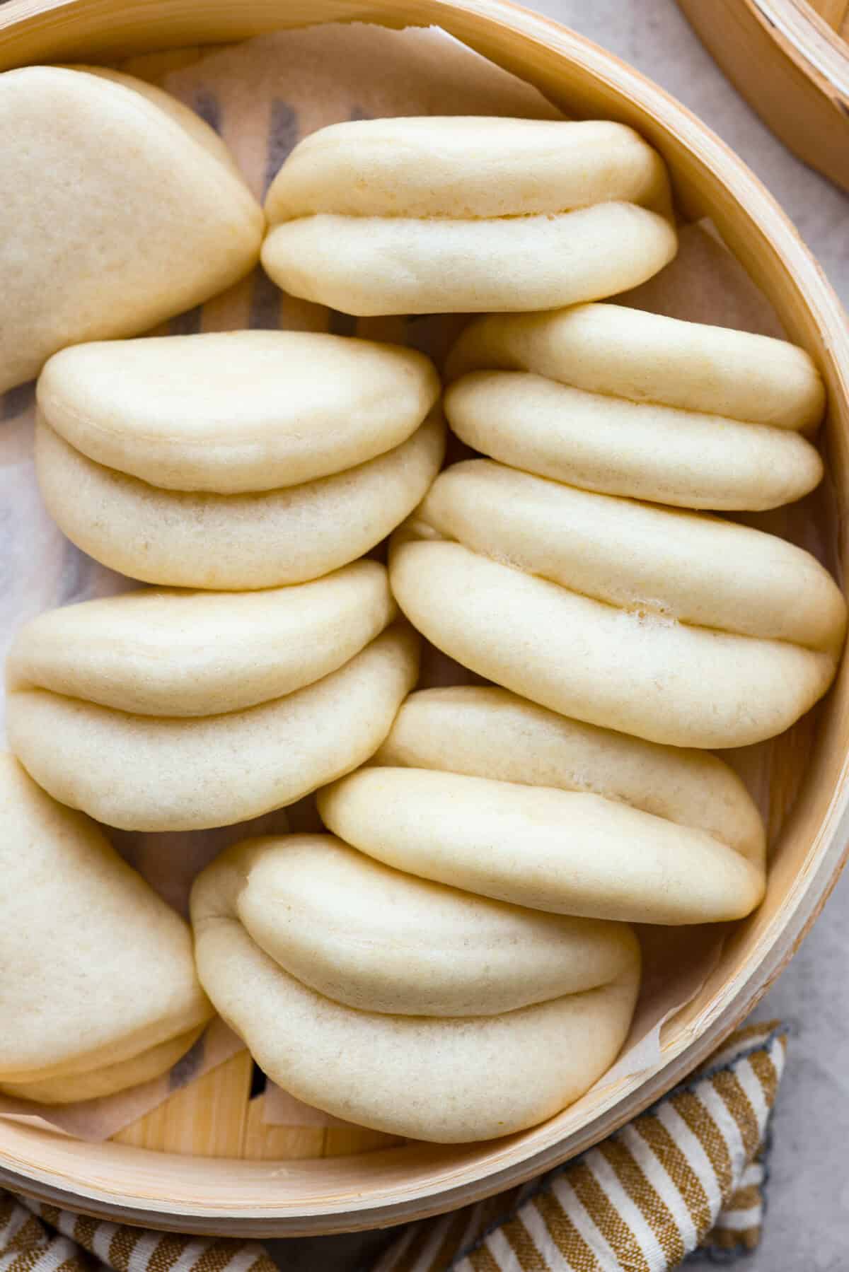 Bao Buns, or Baozi, are soft, pillowy buns made from a slightly sweet dough. They originate from China and are served with different types of fillings. You can enjoy them as a snack, as a side, or with dim sum. Overhead shot of bao buns in a bamboo steamer.