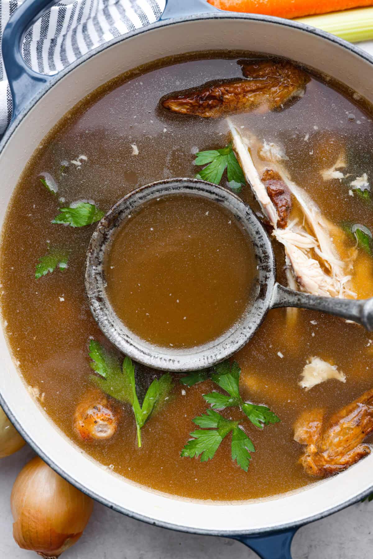 Learn how to make homemade bone broth with all of my top tips and tricks! This easy recipe is a simple combination of wholesome, nutritious ingredients. It's freezer-friendly and great for using in a variety of recipes, from soups, sauces and gravies to casseroles and rice. Overhead shot of bone growth in a pot with a ladle.