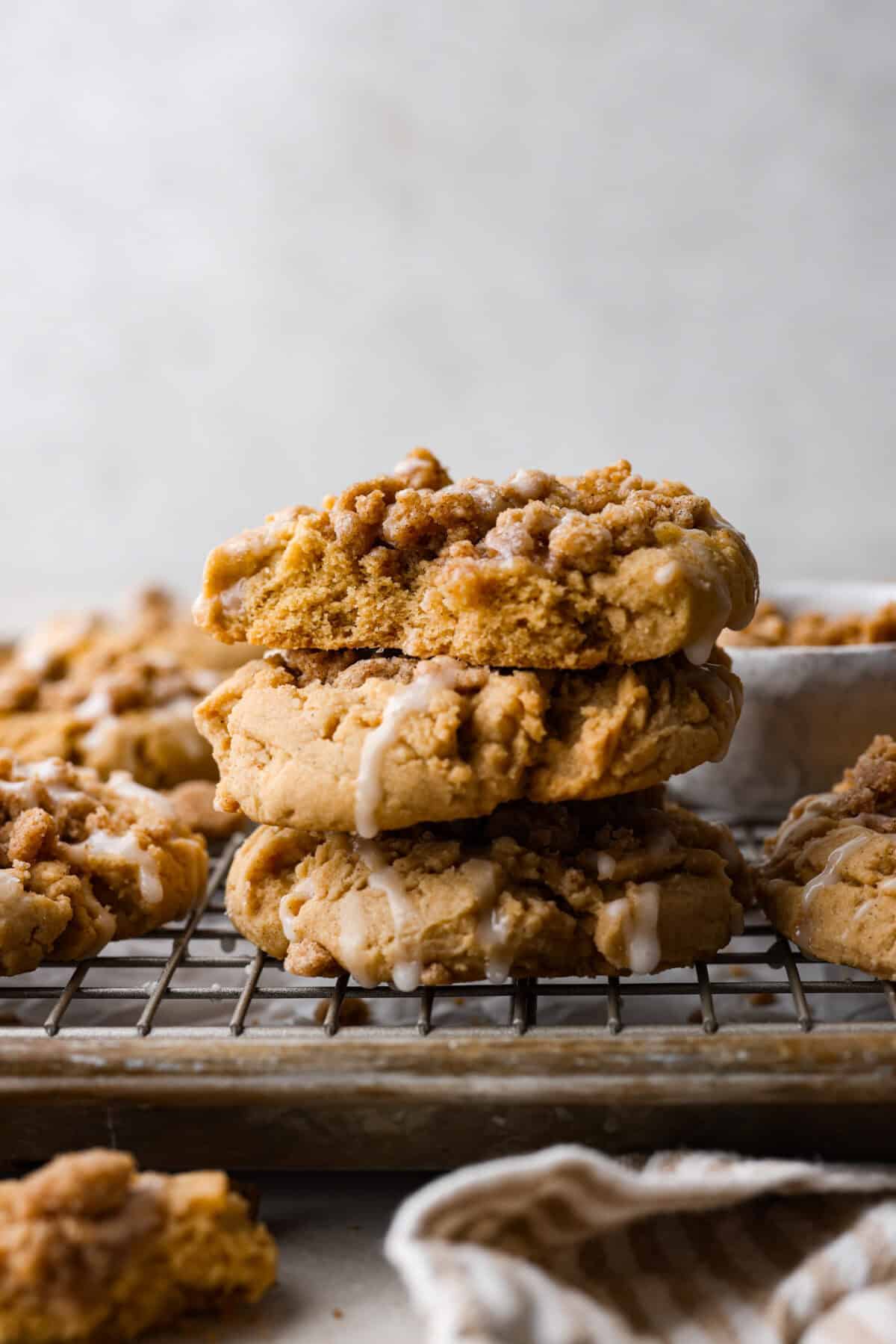 You will absolutely adore these Coffee Cake Cookies! They are loaded with that classic cinnamon sugar flavor, and the crumbly cinnamon streusel is to die for. It’s the perfect treat to enjoy at a special brunch, for the holidays, or a sweet treat for any night of the week. Side shot of coffee cake cookies staked on a cooling rack.