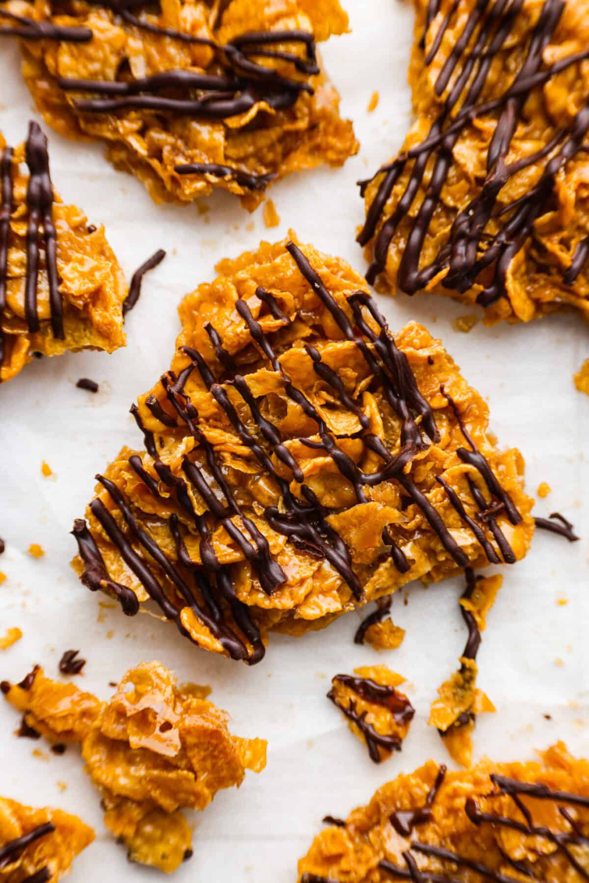 This cornflake brittle crack is crispy, chewy and to die for! With only six ingredients and 8 minutes of prep, you can have this yummy treat ready in no time. This brittle is crunchy cornflakes mixed with a buttery caramel sauce and drizzled in rich dark chocolate. Close up shot of a piece of cornflake brittle crack.