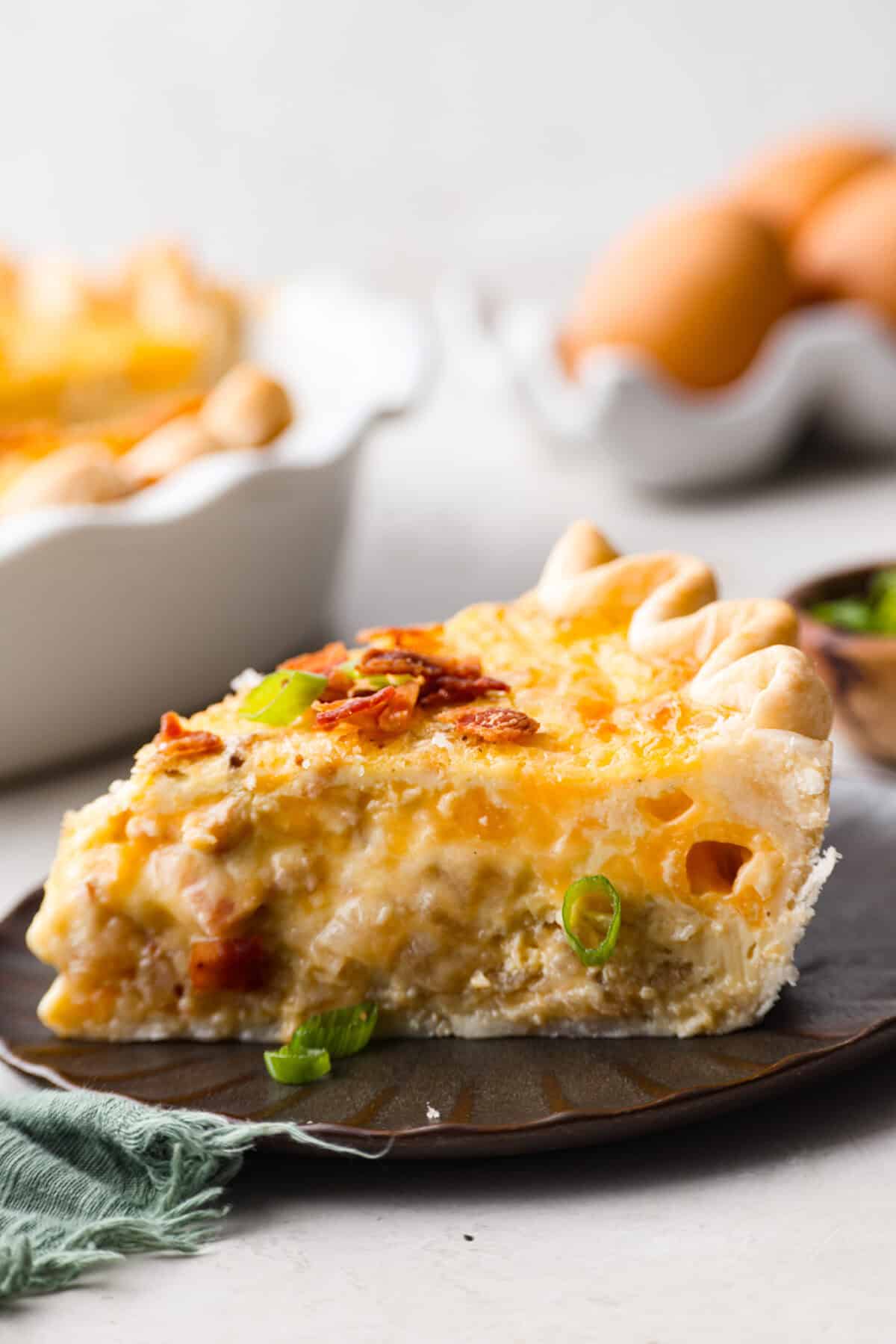Cowboy Quiche is the ultimate hearty, satisfying breakfast that brings classic comfort to the table. It is filled with smoky bacon, caramelized onions, and cheddar cheese, all baked together in a buttery pie crust. It’s rich, savory, and packed with bold flavor. Side shot of a plated piece of cowboy quiche.