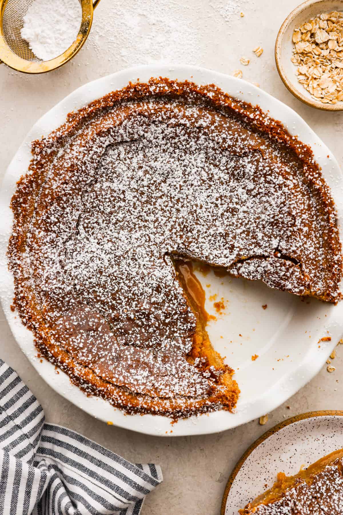 Delicious and addicting, the famous Crack Pie is what made Milk Bar bakery so popular. This copycat recipe is made with a sweet and salty filling tucked inside a crispy oat cookie crust. It’s so good you won’t be able to stop eating it! Overhead shot of baked crack pie with a dusting of powdered sugar over the top.