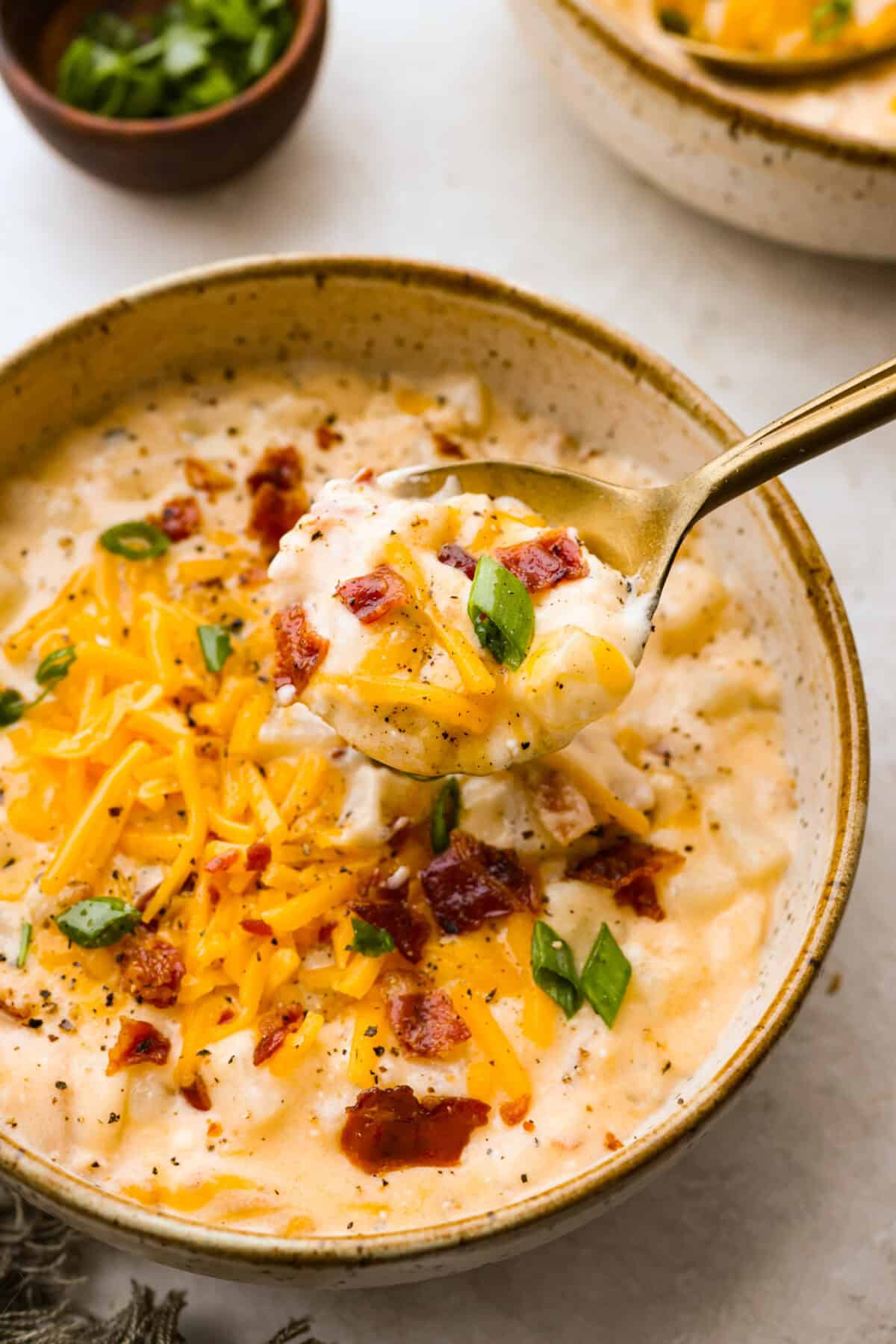 This crock pot crack potato soup is the best and easiest soup you will ever make! It's loaded with creamy cheese, potatoes, hearty chicken, and savory bacon, all seasoned to perfection! Your family will love smelling this cooking when they get home from school! They will like how it tastes even better! Close up shot of crock pot crack potato soup on a spoon over bowl.