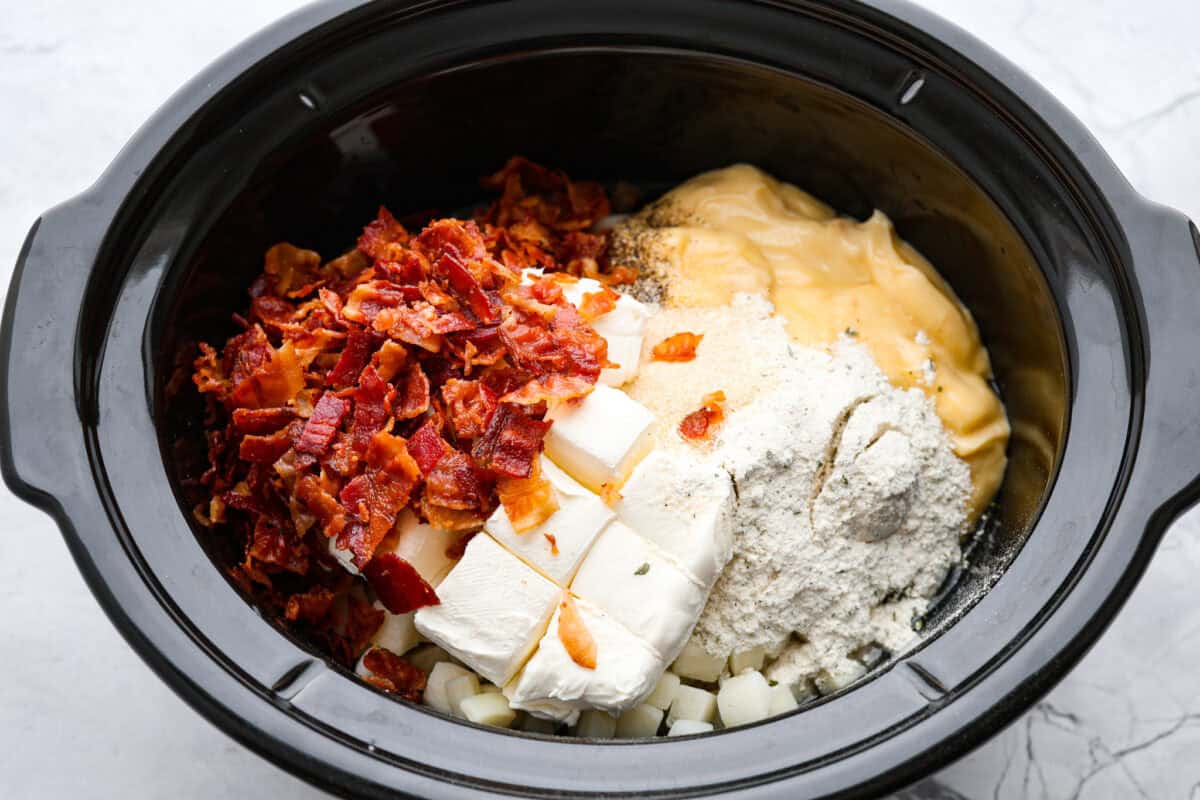 This crock pot crack potato soup is the best and easiest soup you will ever make! It's loaded with creamy cheese, potatoes, hearty chicken, and savory bacon, all seasoned to perfection! Your family will love smelling this cooking when they get home from school! They will like how it tastes even better! Overhead shot of ingredients dumped in a crock pot.