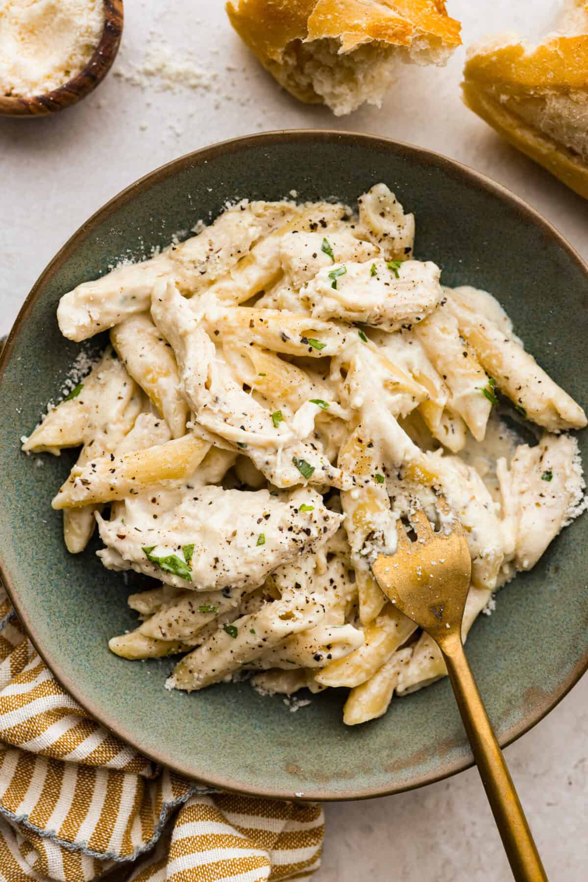 This crockpot chicken alfredo is a family dinner that's packed with flavor! The juicy, tender chicken cooked with creamy, cheesy pasta simply can't be beat! Plus, it’s super easy when your crock pot does all the work! Overhead shot of plated crockpot chicken Alfredo.
