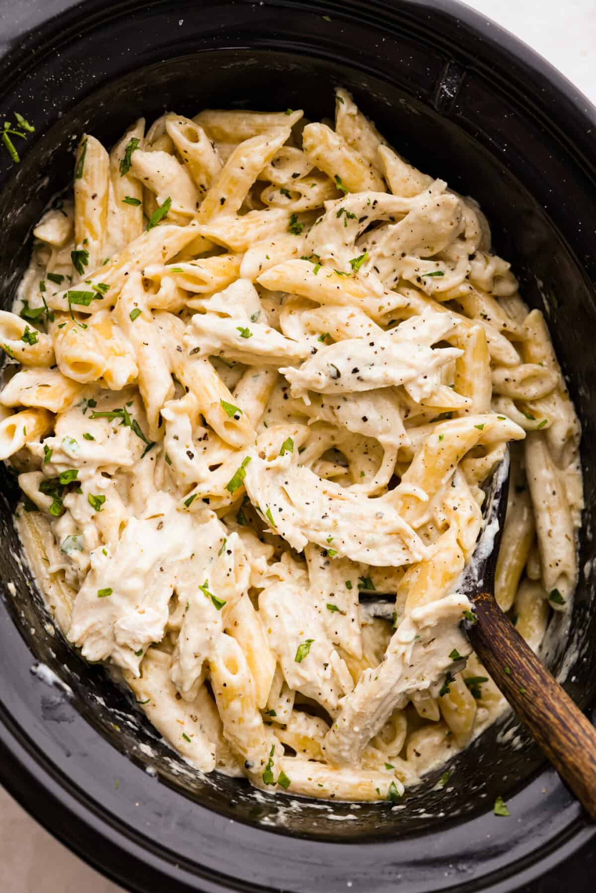 This crockpot chicken alfredo is a family dinner that's packed with flavor! The juicy, tender chicken cooked with creamy, cheesy pasta simply can't be beat! Plus, it’s super easy when your crock pot does all the work! Overhead shot of crockpot chicken Alfredo.