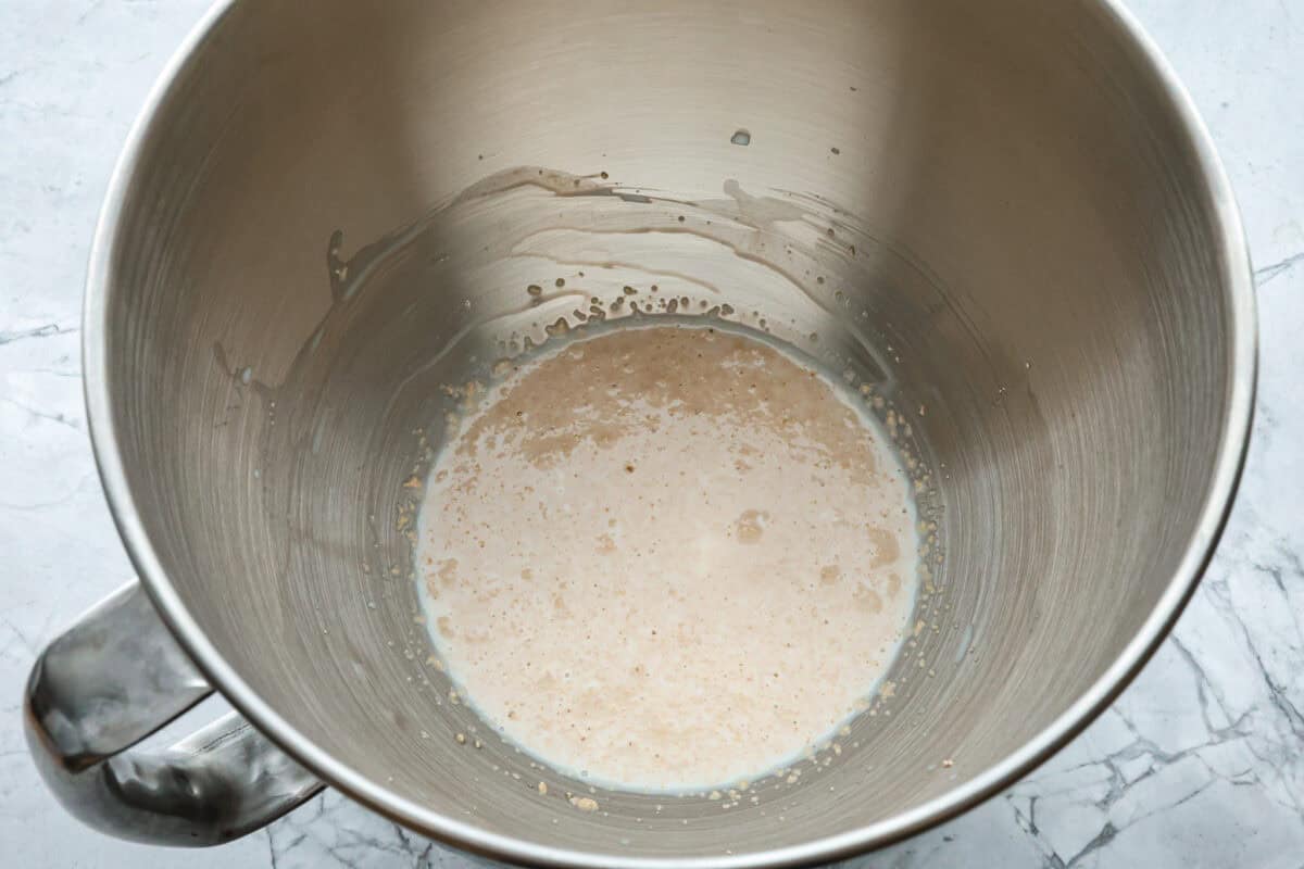 Bao Buns, or Baozi, are soft, pillowy buns made from a slightly sweet dough. They originate from China and are served with different types of fillings. You can enjoy them as a snack, as a side, or with dim sum. Overhead shot of water, milk, sugar and yeast in a stand mixer bowl.