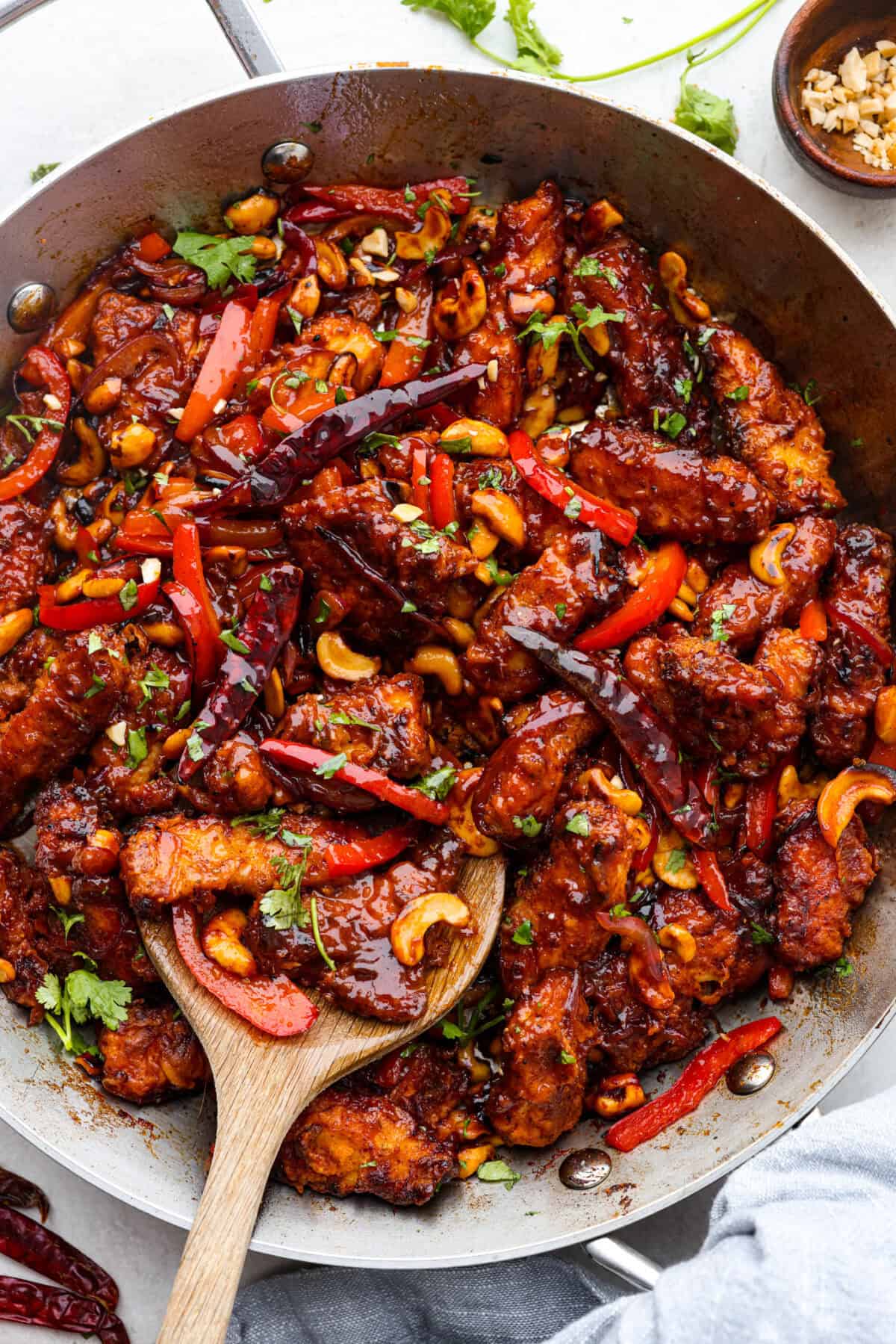 Dragon Chicken is a spicy and flavorful dish featuring tender breaded chicken stir-fried with vegetables and coated in a rich, tangy, and slightly sweet sauce. It's a crowd favorite for those who enjoy a fiery twist on the classic stir-fry! Overhead shot of dragon chicken in a wok with a wooden spoon.