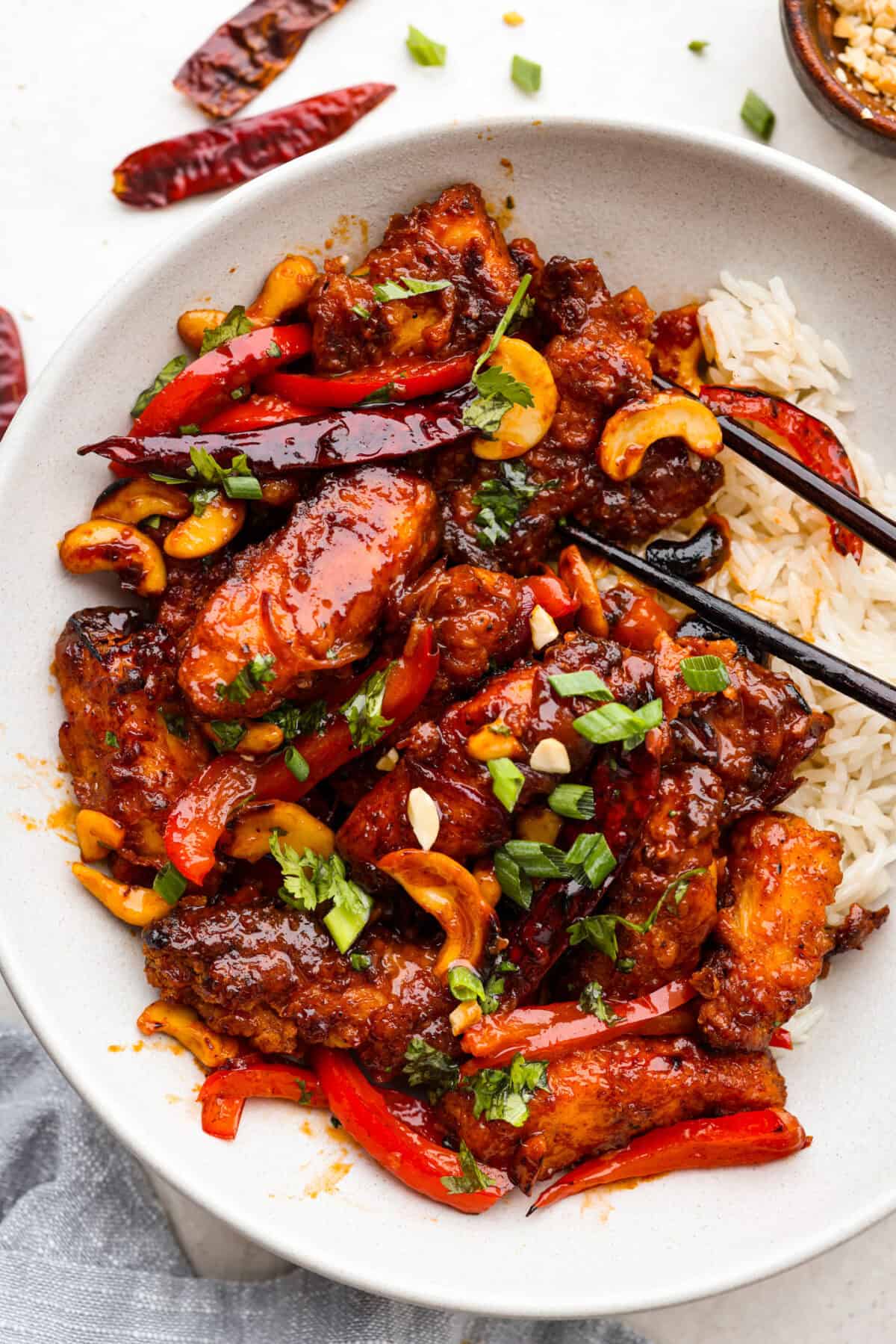 Dragon Chicken is a spicy and flavorful dish featuring tender breaded chicken stir-fried with vegetables and coated in a rich, tangy, and slightly sweet sauce. It's a crowd favorite for those who enjoy a fiery twist on the classic stir-fry! Overhead shot of plated dragon chicken with rice and chopsticks.
