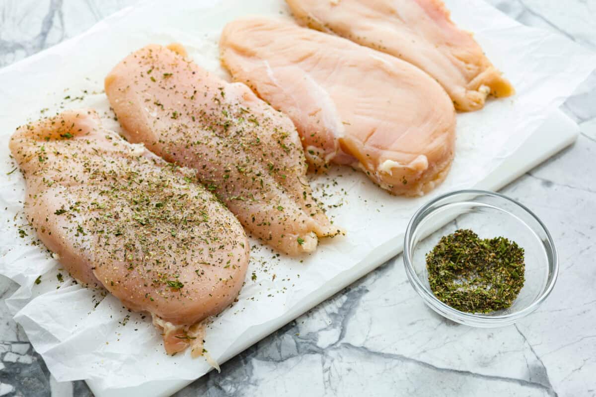 Garlic Butter Chicken is a rich and flavorful one-pan recipe that's on the dinner table in just 30 minutes! Well-seasoned, tender chicken breasts are pan-seared and then nestled in a simple yet tasty sauceย made with vinegar, broth, butter, shallots, and plenty of garlic. Angle shot of chicken breasts being coated in seasonings.