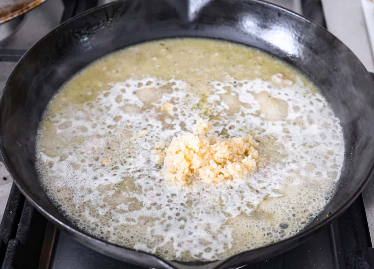 Garlic Butter Chicken is a rich and flavorful one-pan recipe that's on the dinner table in just 30 minutes! Well-seasoned, tender chicken breasts are pan-seared and then nestled in a simple yet tasty sauceย made with vinegar, broth, butter, shallots, and plenty of garlic. Angle shot of chicken broth and white wine mixture with garlic added.