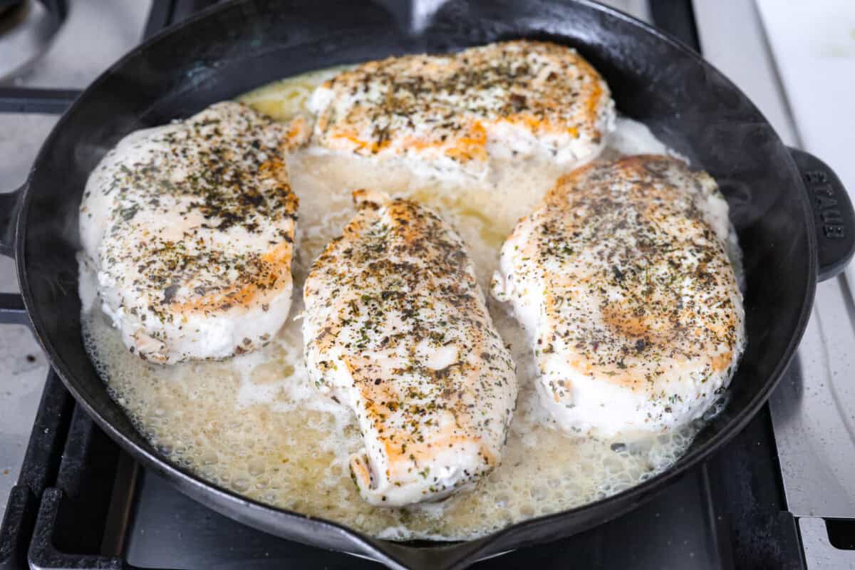 Garlic Butter Chicken is a rich and flavorful one-pan recipe that's on the dinner table in just 30 minutes! Well-seasoned, tender chicken breasts are pan-seared and then nestled in a simple yet tasty sauceย made with vinegar, broth, butter, shallots, and plenty of garlic. Angle shot of browned chicken breasts in broth and garlic mixture in skillet.