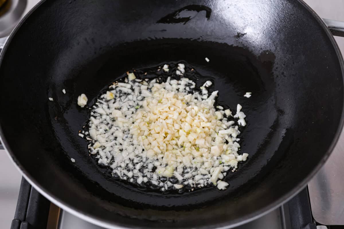 Garlic fried rice is one of the most common Filipino rice dishes. It combines leftover rice with crispy fried garlic, all tossed together with seasonings to create something simple that is incredibly flavorful! Angle shot of minced garlic added to oil in a wok.