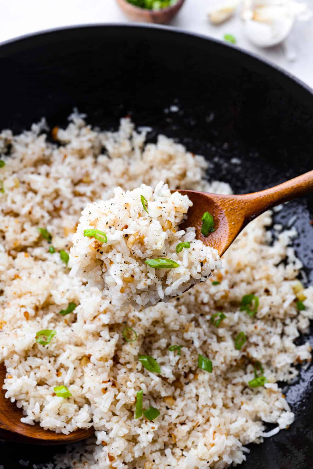 Garlic fried rice is one of the most common Filipino rice dishes. It combines leftover rice with crispy fried garlic, all tossed together with seasonings to create something simple that is incredibly flavorful! Close up shot of garlic fried rice on a wooden serving spoon.