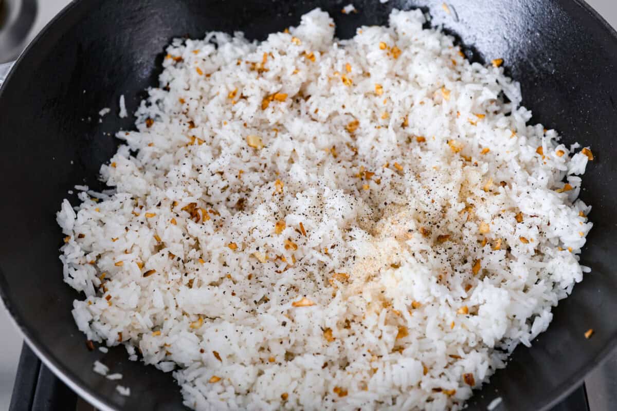 Garlic fried rice is one of the most common Filipino rice dishes. It combines leftover rice with crispy fried garlic, all tossed together with seasonings to create something simple that is incredibly flavorful! Overhead shot of seasonings added to the rice in the pan.