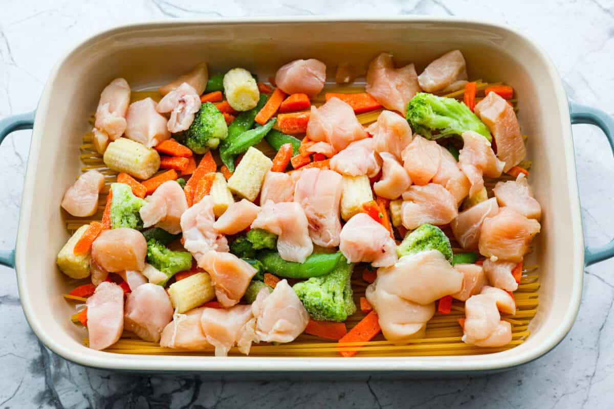 Honey Sesame Chicken Noodle Bake is the perfect dinner solution when you need something incredibly tasty and totally fuss-free! This is a complete meal with delicious Asian flavors in one pan, without needing to pre-cook anything. Overhead shot of chicken added to the veggies and noodles.