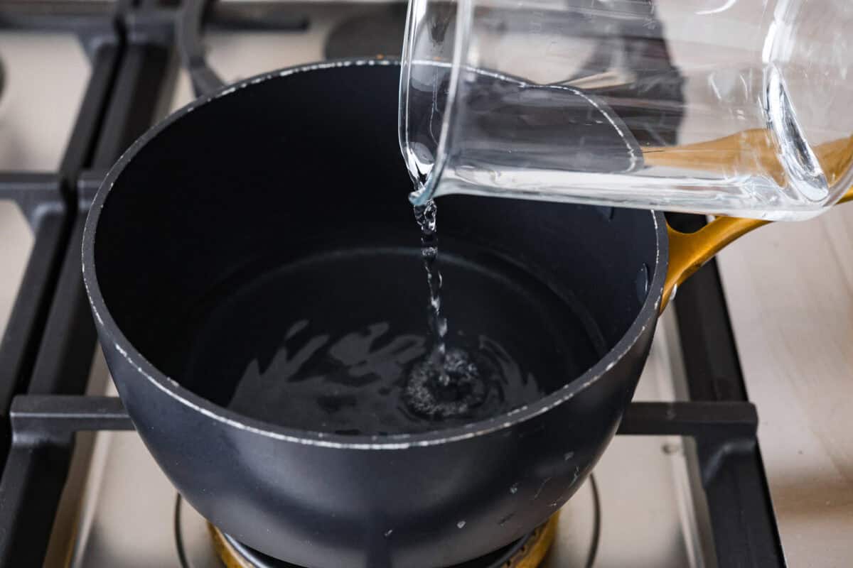 Learn how to temper chocolate for all your chocolate dipping and candy-making needs! Tempering chocolate can be intimidating but my how-to guide will help you every step of the way. First photo of water adding to a pot to make a double boiler.
