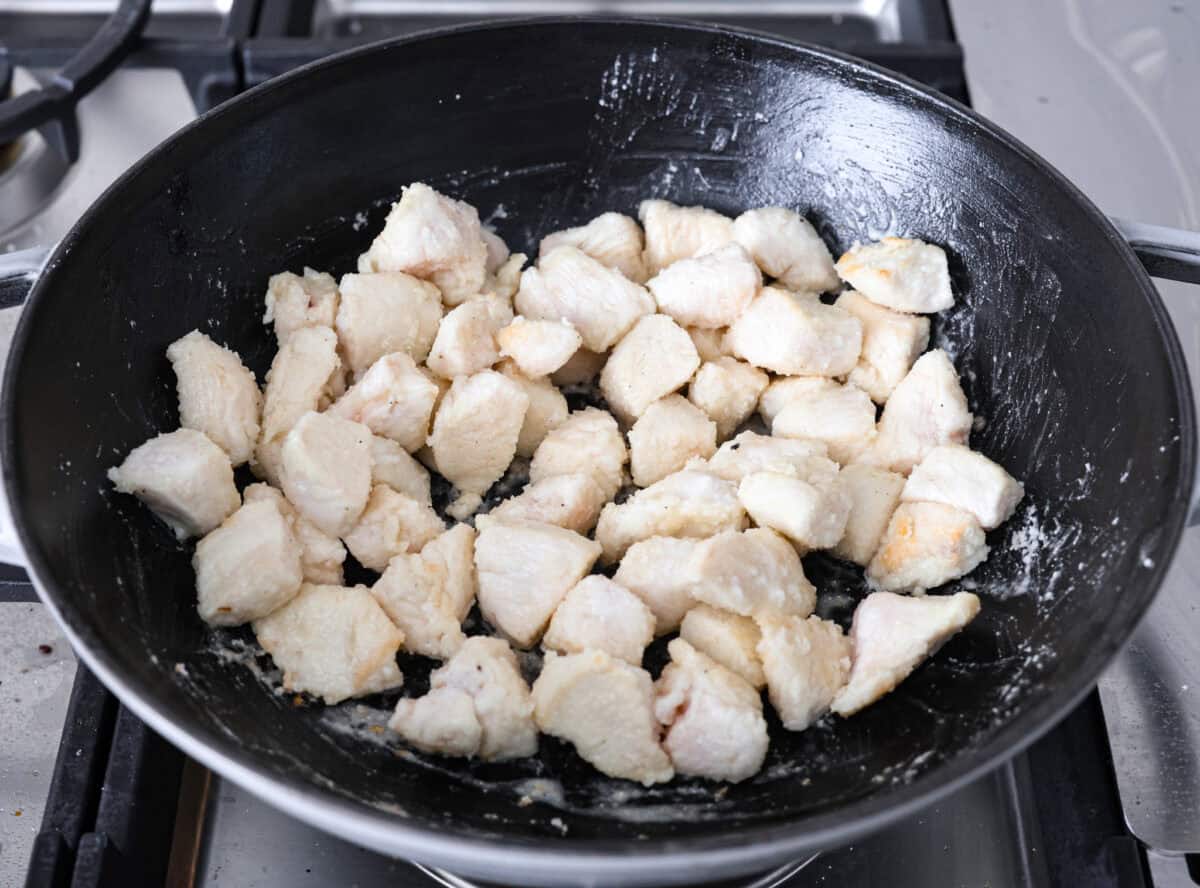 Delicious Jalapeño Chicken will become an instant favorite with the very first bite. Tender chicken pieces are cooked with jalapeños and then coated in a sticky, sweet, and spicy sauce. Serve over rice for an easy meal. You'll be craving it on repeat! Angle shot of the chicken being cooked in a skillet on the stove top.