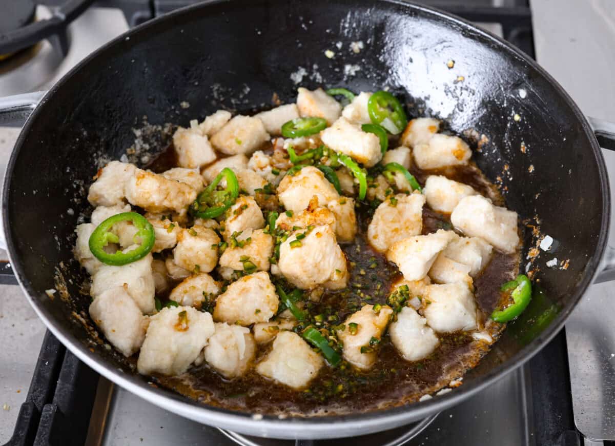 Delicious Jalapeño Chicken will become an instant favorite with the very first bite. Tender chicken pieces are cooked with jalapeños and then coated in a sticky, sweet, and spicy sauce. Serve over rice for an easy meal. You'll be craving it on repeat! Angle shot of browned chicken, cooked jalapeños, garlic and onions with sauce poured over the top.