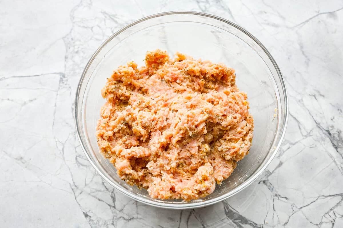 With creamy Tuscan flavors, these Marry Me Meatballs are an instant crowd favorite! It doesn't get much better than Italian seasoned chicken meatballs nestled in a creamy, cheesy sauce with sun-dried tomatoes and fresh herbs. Overhead shot of meatball ingredients mixed together in a bowl.
