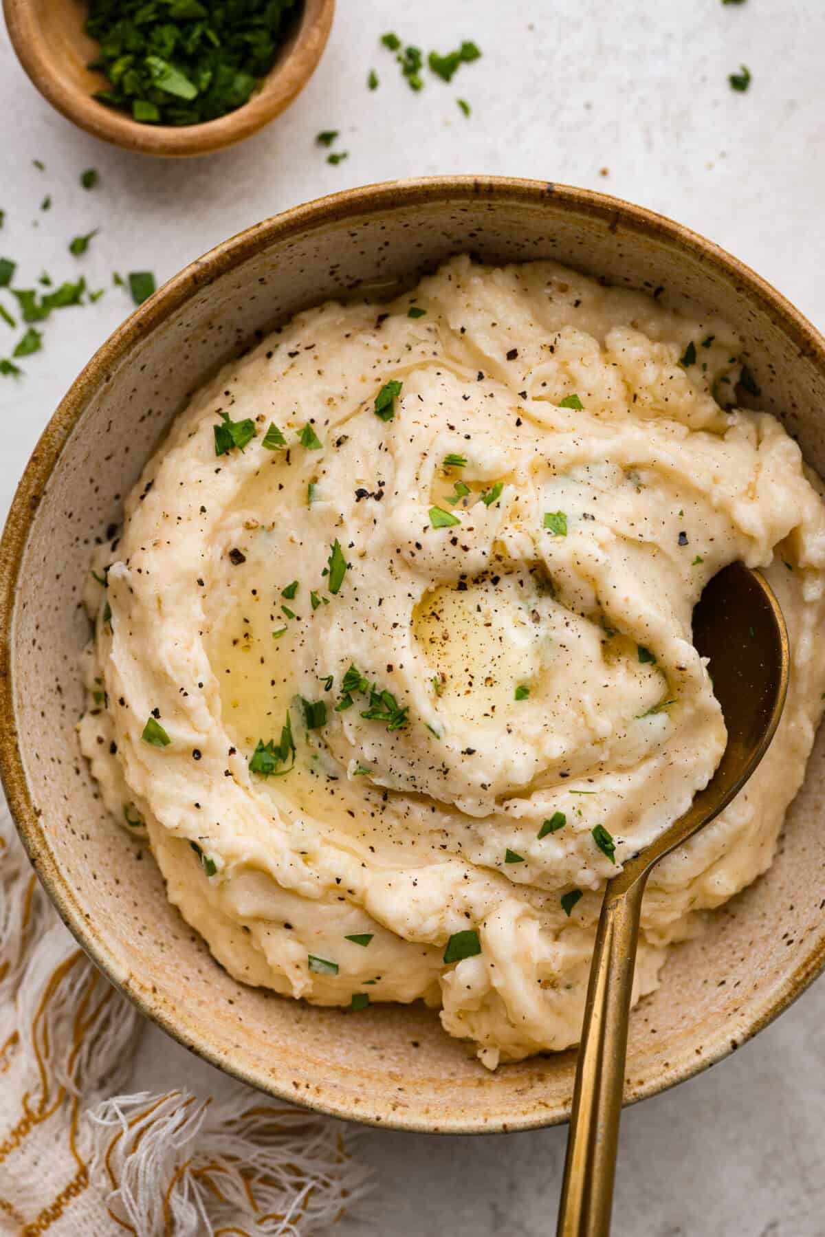 Million dollar mashed potatoes are unmatched when it comes to creamy velvety mashed potatoes. They get their intense flavors and smooth texture from letting the potatoes slow cook in chicken broth then mixing them with cream cheese, butter and garlic. Overhead shot of plated million dollar mashed potatoes.