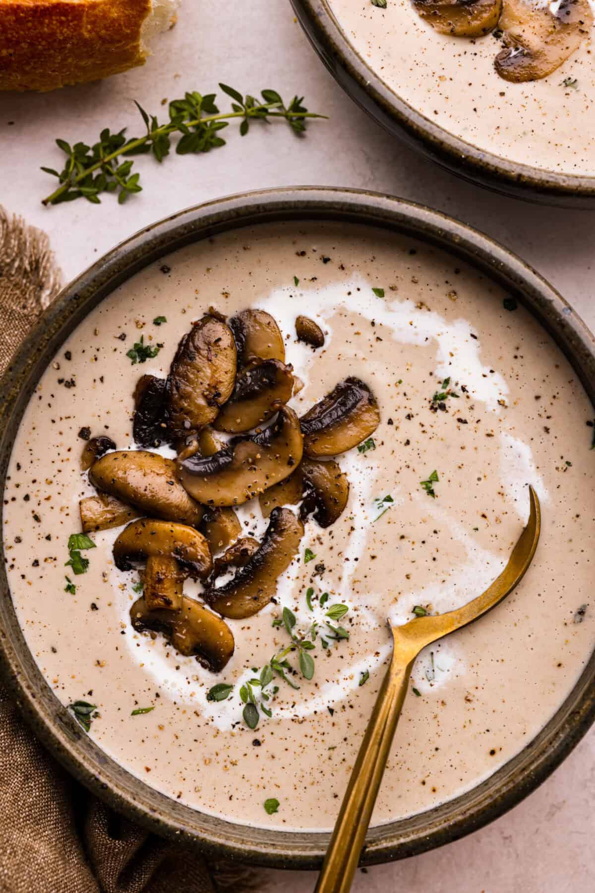 Mushroom bisque is full of cream and garlic-infused mushrooms, all blended to make a thick, rich, and beyond flavorful soup! You will want to drink this straight from your bowl! Overhead shot of a bowl of mushroom bisque with sautéed mushrooms on top.