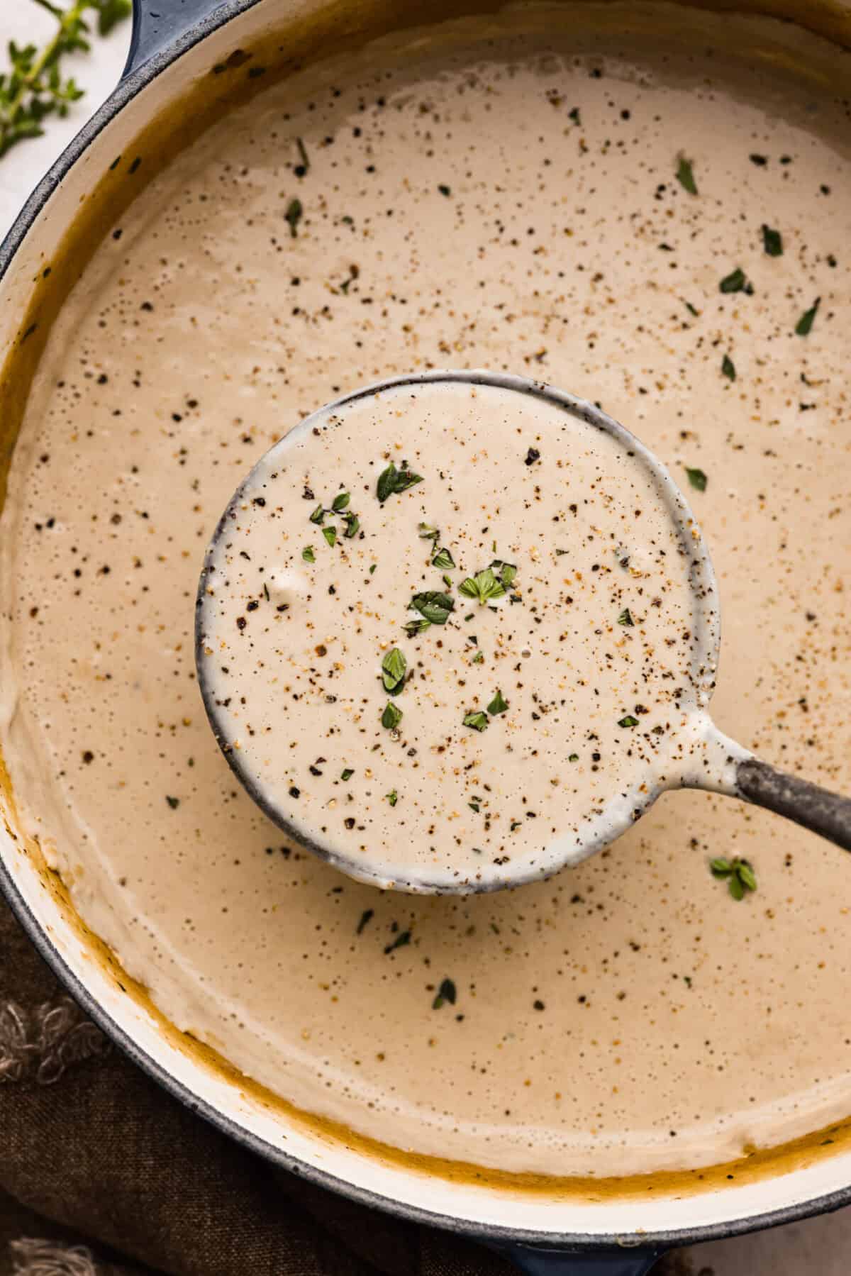 Mushroom bisque is full of cream and garlic-infused mushrooms, all blended to make a thick, rich, and beyond flavorful soup! You will want to drink this straight from your bowl! Close up shot of a ladle full of mushroom bisque.