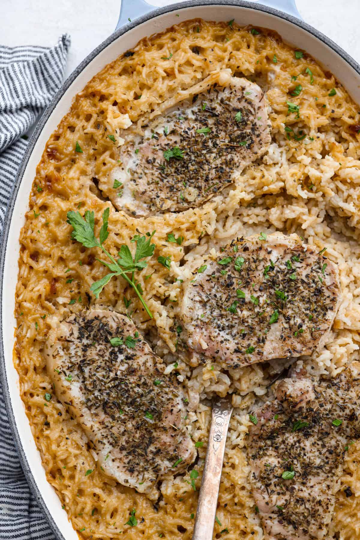 No Peek Pork Chops and Rice is comfort food at its best! Creamy, savory riceย and tender pork chops are baked together in the same pan with less than 10 minutes of prep. This dish is a go-to for busy weeknights and is perfect when you need a tasty meal without much hassle! Overhead shot of no peek pork chops and rice in a baking dish.