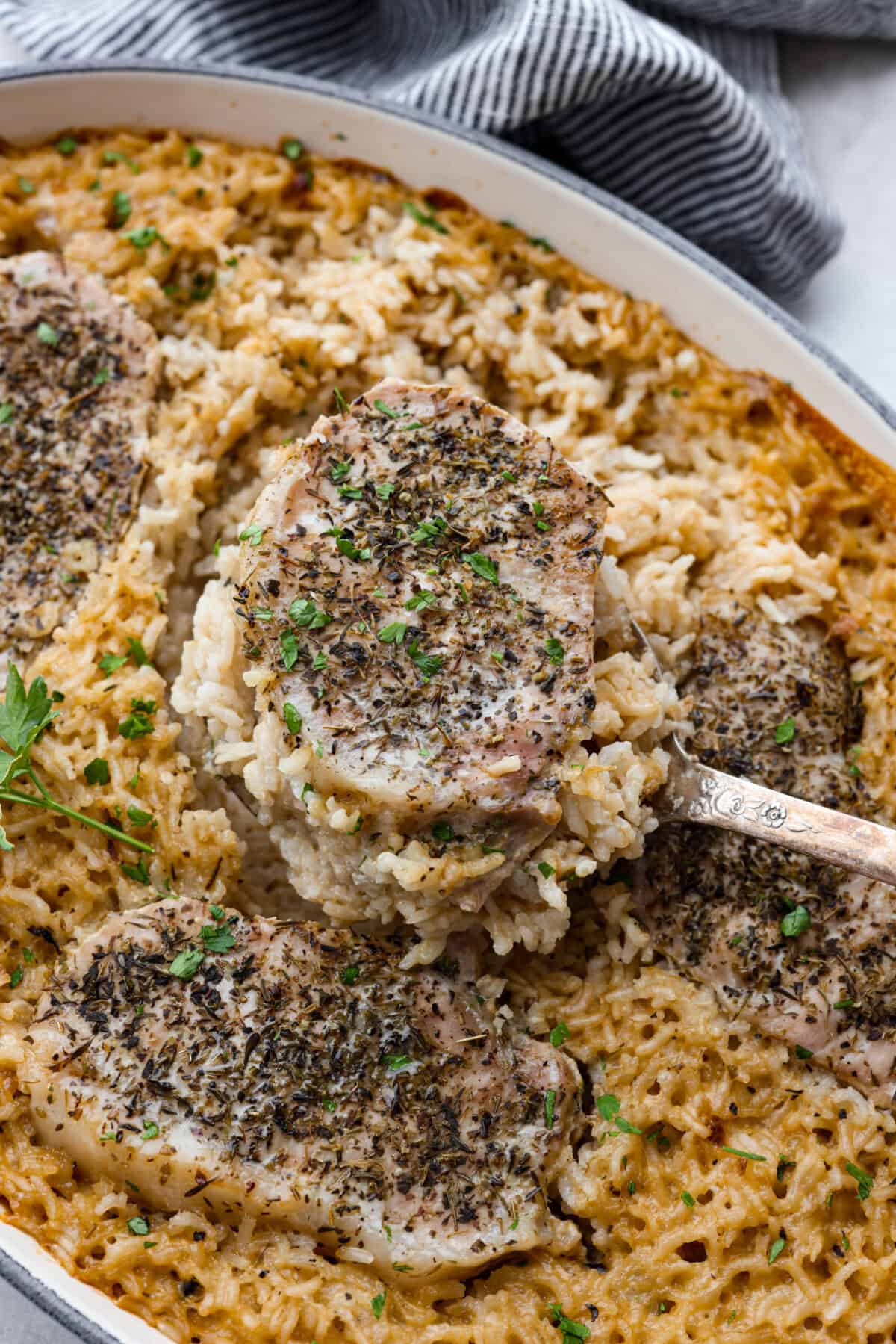 No Peek Pork Chops and Rice is comfort food at its best! Creamy, savory riceย and tender pork chops are baked together in the same pan with less than 10 minutes of prep. This dish is a go-to for busy weeknights and is perfect when you need a tasty meal without much hassle! Close up shot of no peek pork chops and rice.