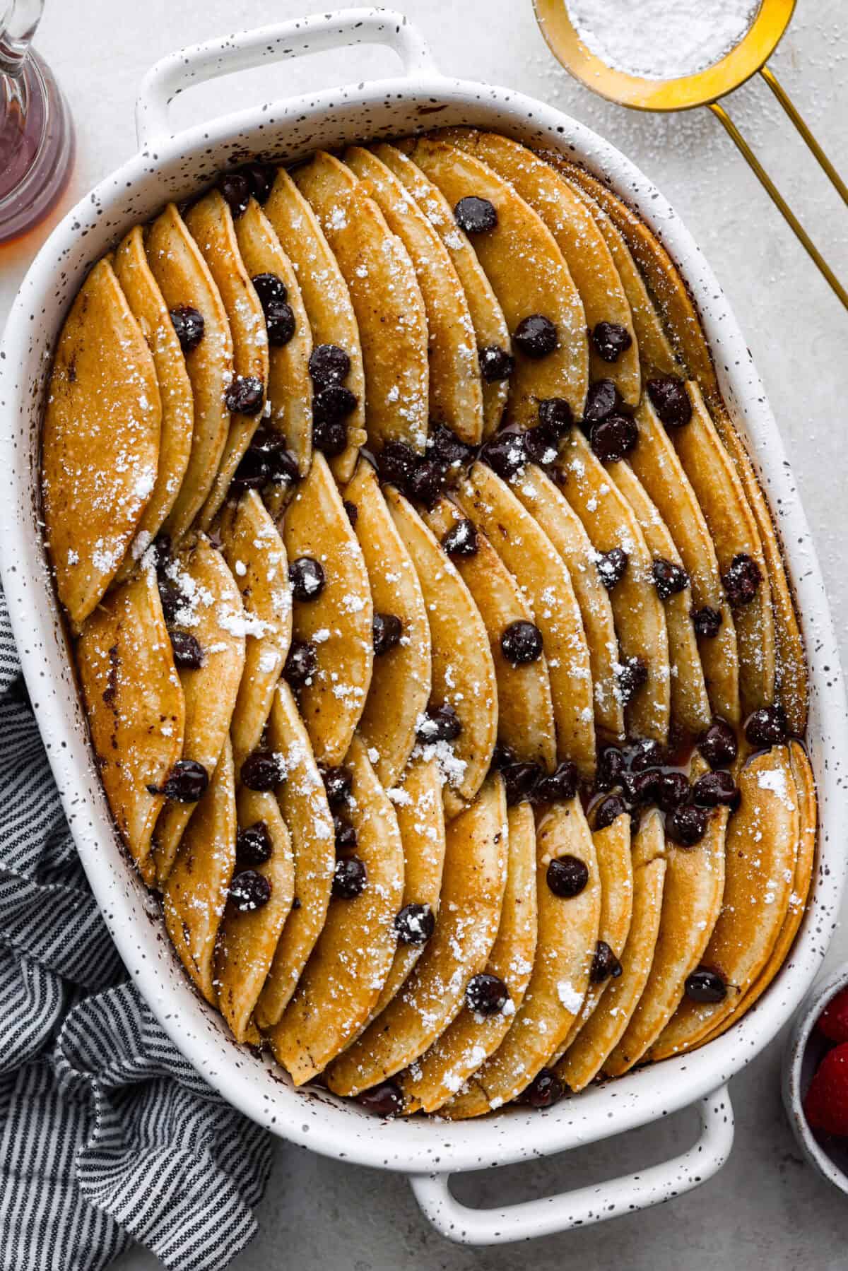 Pancake Casserole is a fun new Christmas or Easter breakfast idea. It has lots of buttery pancakes soaked overnight in a creamy custard, is baked to perfection, and served with your favorite toppings! Overhead shot of pancake casserole.