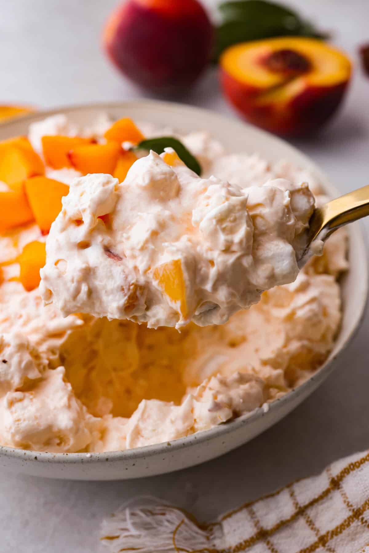 t's peach season which means you have to make this Peach Fluff Salad! It's a creamy, fruity dessert that hits all the right notes and is packed with fresh peaches! A close up of a spoonful of fresh peach fluff salad.