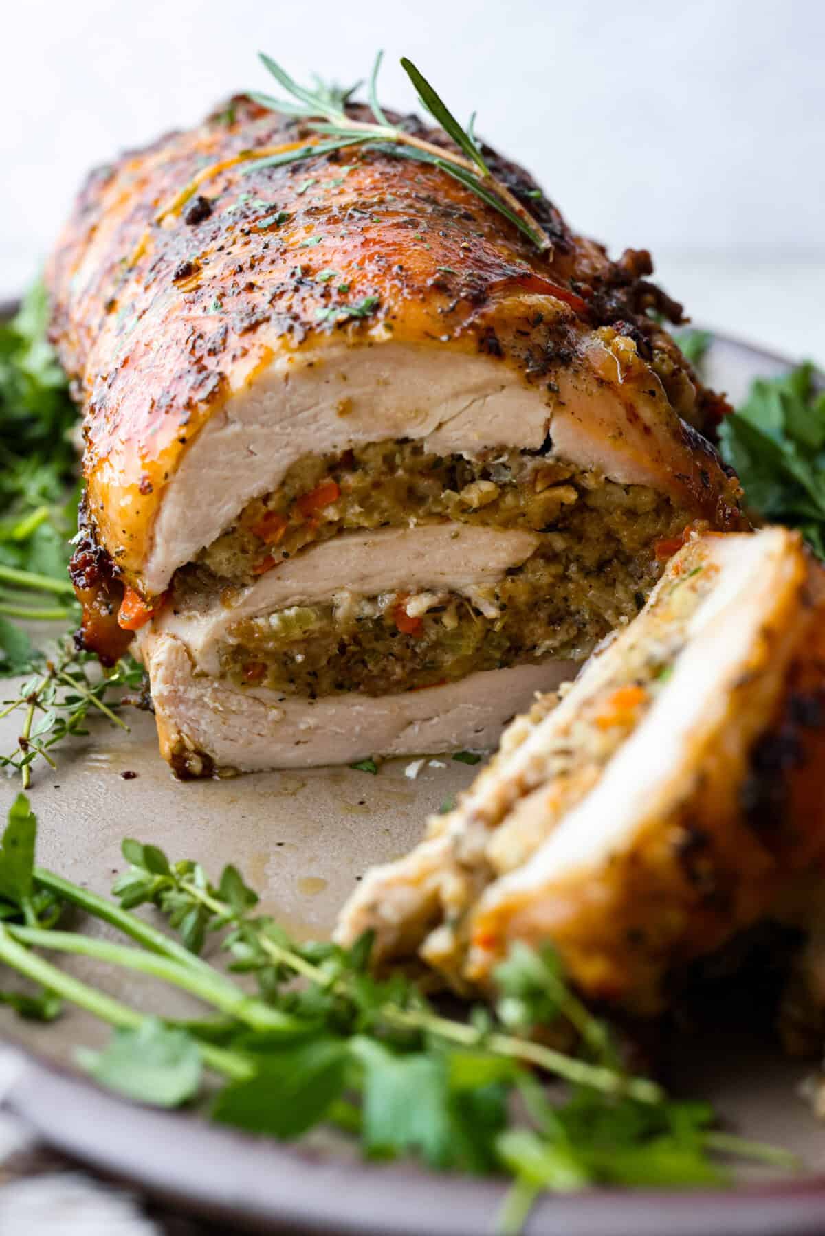 Make Turkey Roulade your new Thanksgiving tradition! Boneless turkey breast gets flattened and rolled with sausage stuffing inside. The turkey turns out incredibly moist and is infused with your favorite Thanksgiving flavors. It takes far less time than traditional turkey and will make Thanksgiving day easy and delicious! Close view of turkey roulade on a platter and sliced.