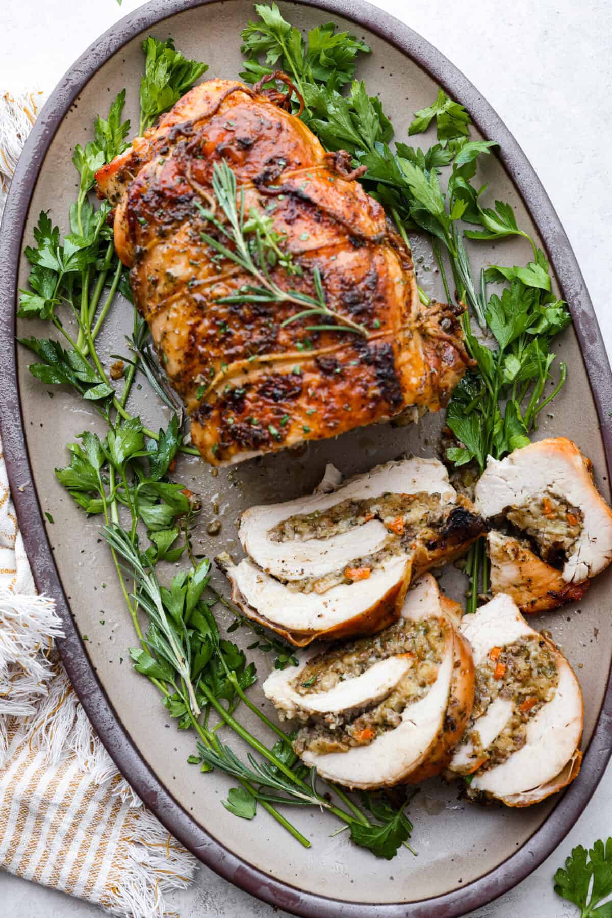 Make Turkey Roulade your new Thanksgiving tradition! Boneless turkey breast gets flattened and rolled with sausage stuffing inside. The turkey turns out incredibly moist and is infused with your favorite Thanksgiving flavors. It takes far less time than traditional turkey and will make Thanksgiving day easy and delicious! Top view of turkey roulade on a platter.