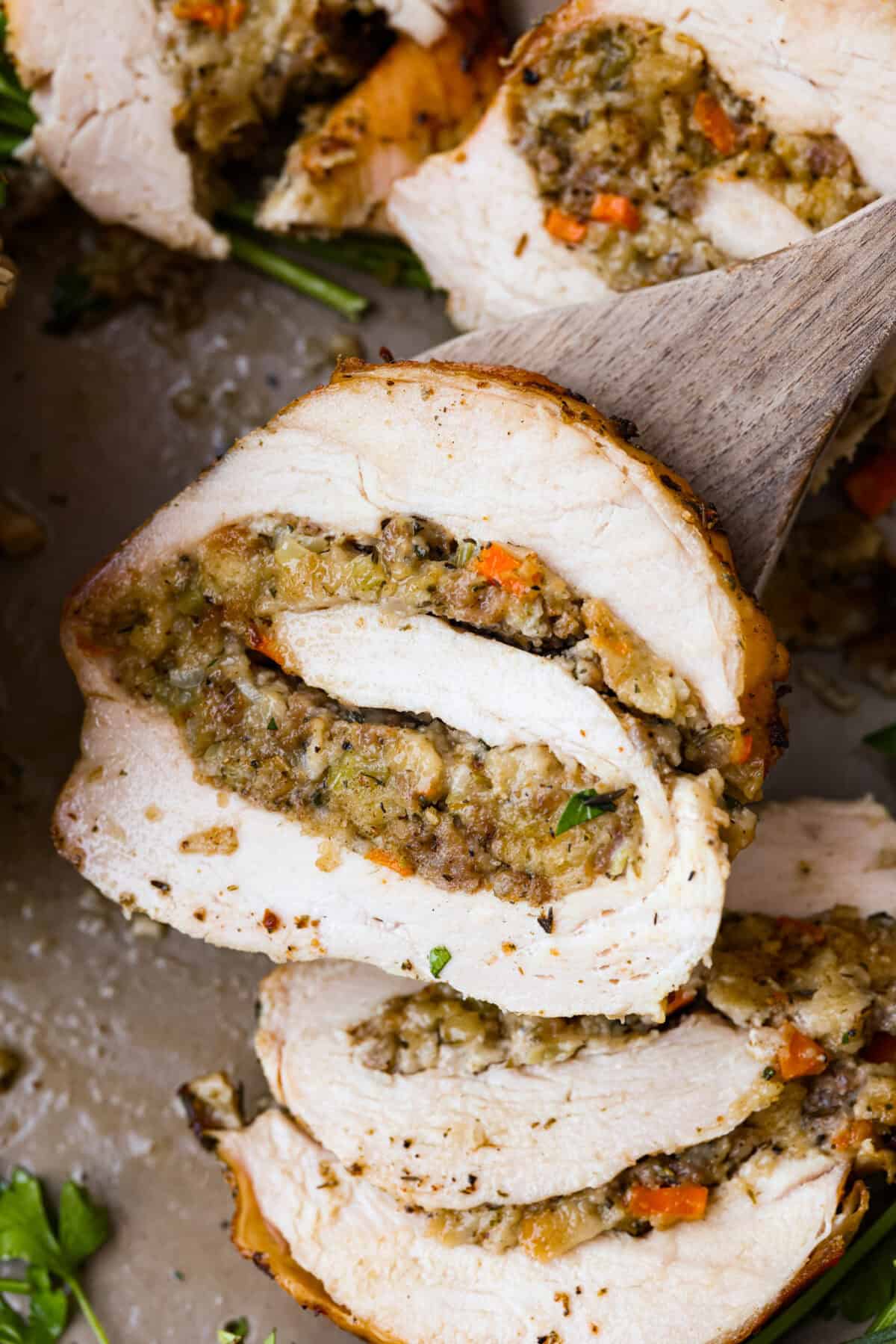 Make Turkey Roulade your new Thanksgiving tradition! Boneless turkey breast gets flattened and rolled with sausage stuffing inside. The turkey turns out incredibly moist and is infused with your favorite Thanksgiving flavors. It takes far less time than traditional turkey and will make Thanksgiving day easy and delicious! Close view of a slice of turkey roulade.