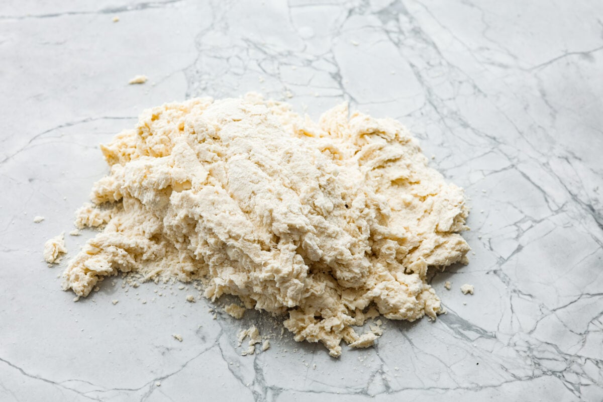 Cream cheese biscuits have a slight twist to the classic version. With the added cream cheese, they have a softer, more fluffy texture with an added tangy flavor that is so good! Overhead shot of flour, butter and buttermilk mixture on a countertop.