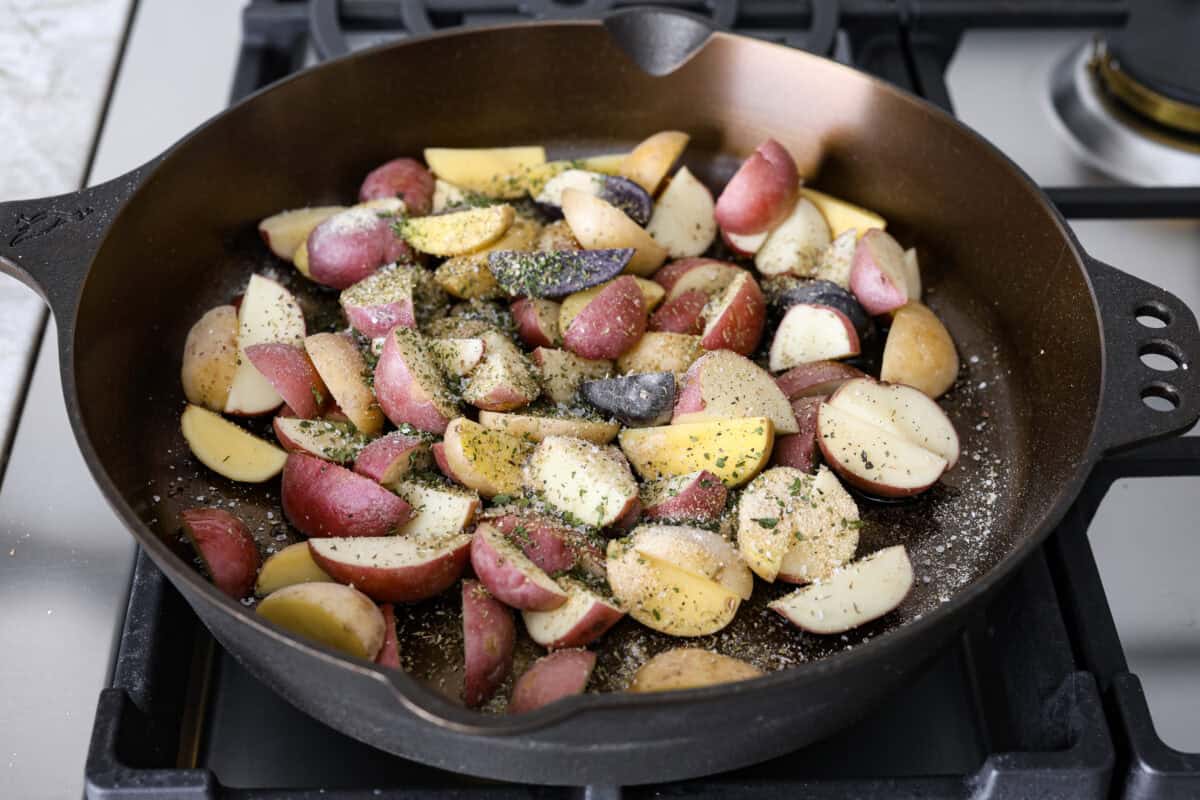 This sausage and potato skillet recipe is meant to be a simple one skillet meal! It has tender baby potatoes, smoked sausage, peppers, and delicious seasonings that take it over the top. It's hearty, satisfying and loaded with flavor! Second photo of the potatoes cooking in a skillet.