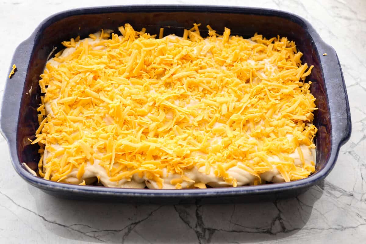 Hamburger Potato Casserole is hearty, filling, and great for family dinners. It's full of tender potatoes and ground beef, smothered in a deliciously creamy sauce, and covered in melty cheese. Overhead shot of first three layers of casserole in the baking dish.