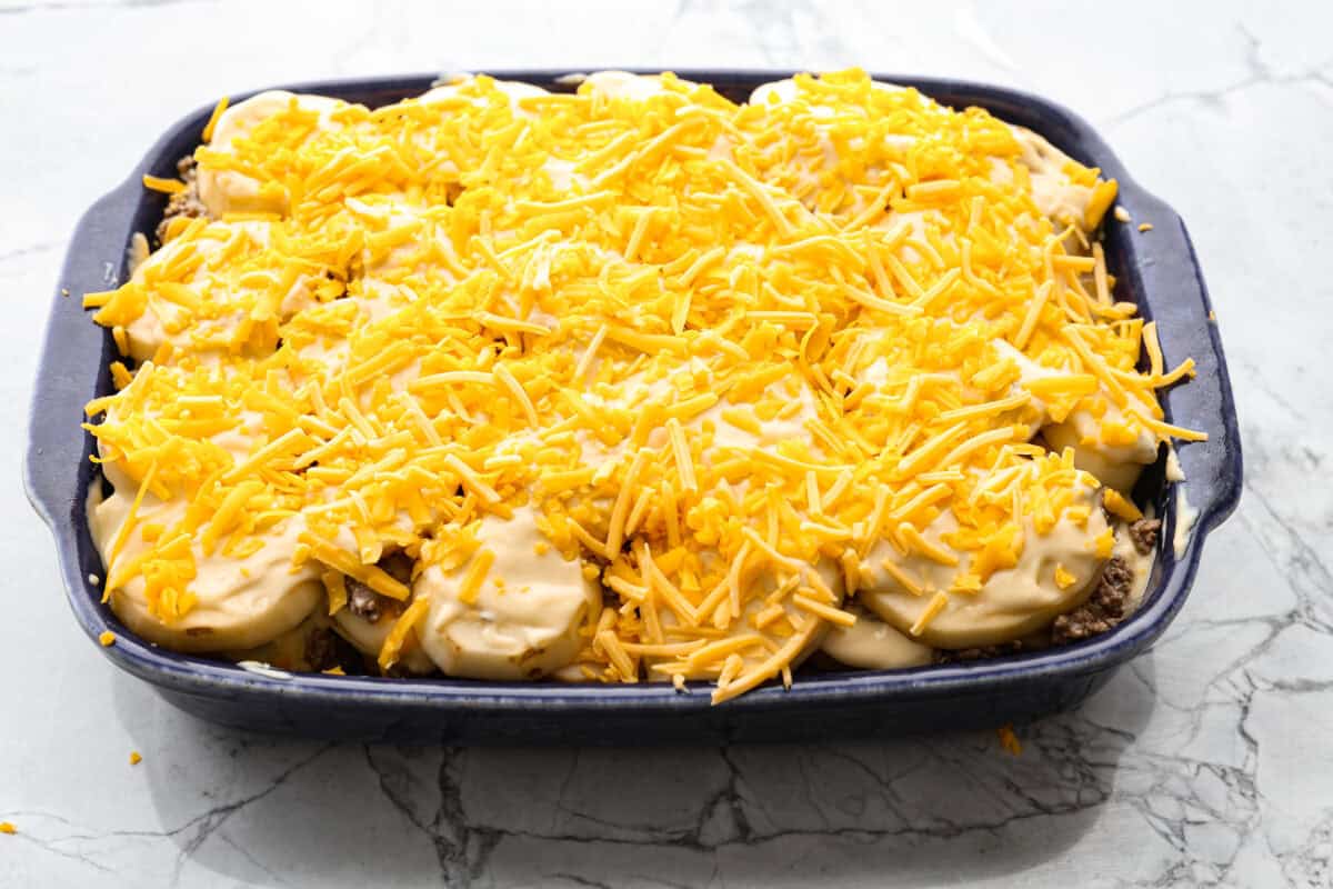 Hamburger Potato Casserole is hearty, filling, and great for family dinners. It's full of tender potatoes and ground beef, smothered in a deliciously creamy sauce, and covered in melty cheese. Overhead shot of hamburger potato casserole ready to go in the oven.