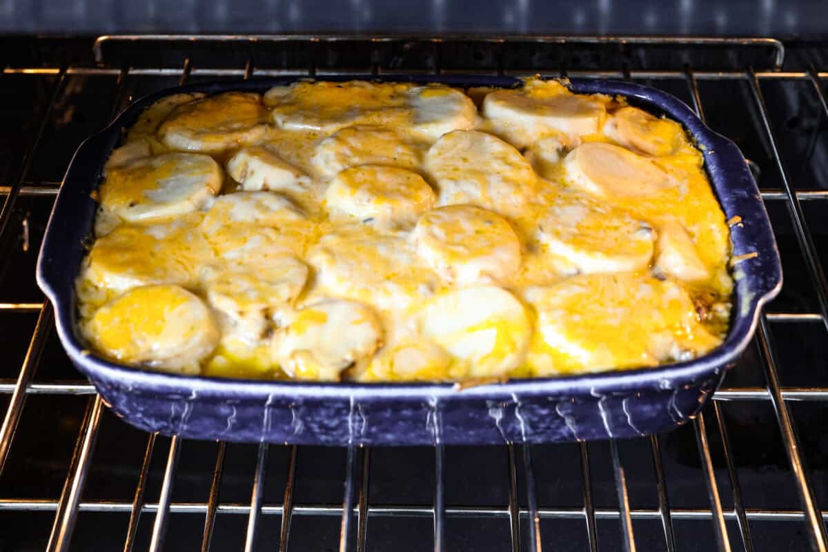 Hamburger Potato Casserole is hearty, filling, and great for family dinners. It's full of tender potatoes and ground beef, smothered in a deliciously creamy sauce, and covered in melty cheese. Angle shot of casserole being baked in the oven.