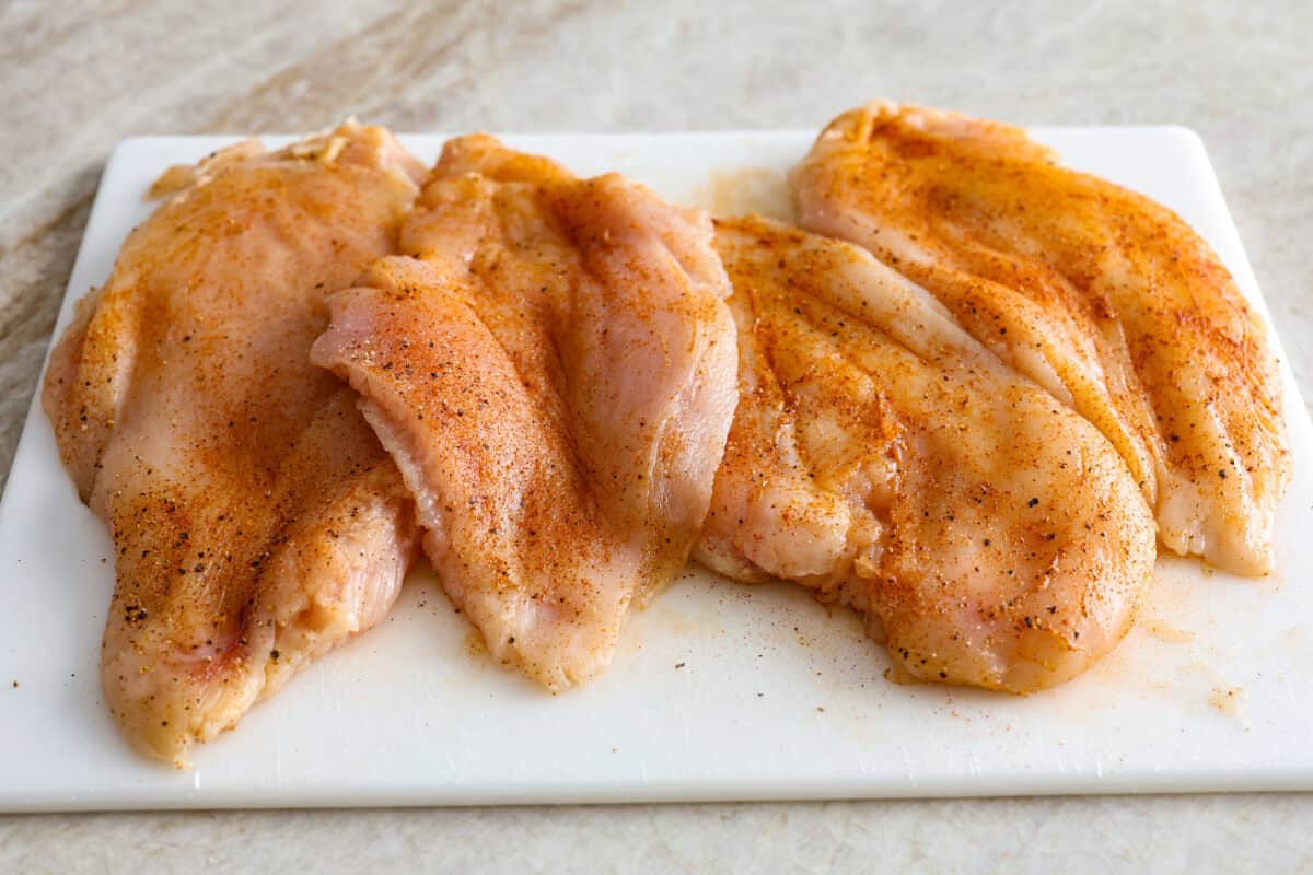 Million Dollar Chicken features juicy baked chicken topped with a creamy, cheesy layer that’s bursting with flavor. The crispy bacon and crunchy almonds really take this to the next level. Enjoy with rice, pasta, vegetables, or any of your favorite sides! Overhead shot of seasoned chicken breasts on a cutting board.