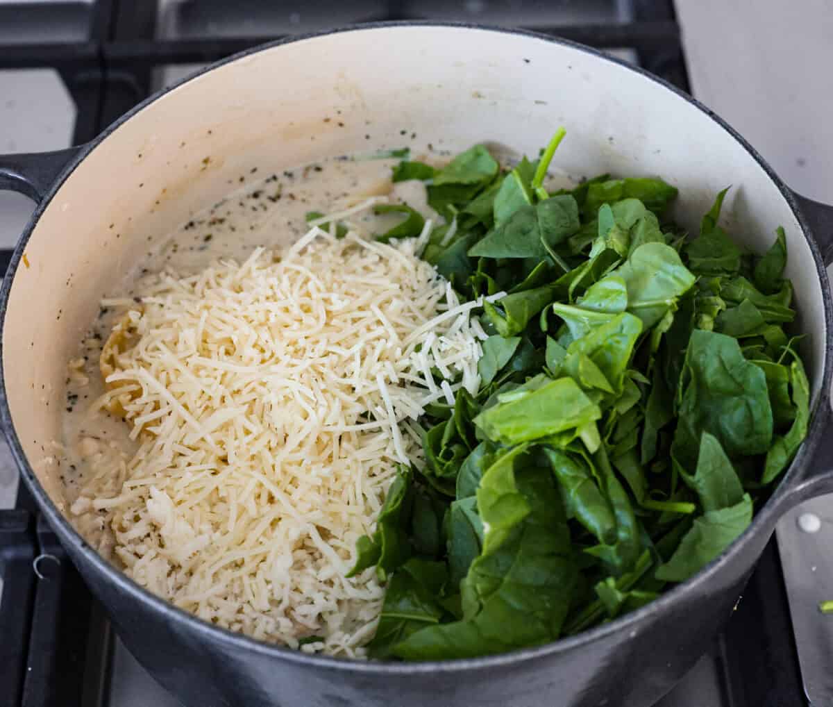 Comforting White Lasagna Soup is warm, creamy, and packed with rich flavors. With its hearty mix of chicken, noodles, white beans, and cheese, it’s a guaranteed crowd-pleaser. Deconstructed white lasagna in a satisfying soup! Overhead shot of the cheese and spinach added to the white lasagna soup in a pot.