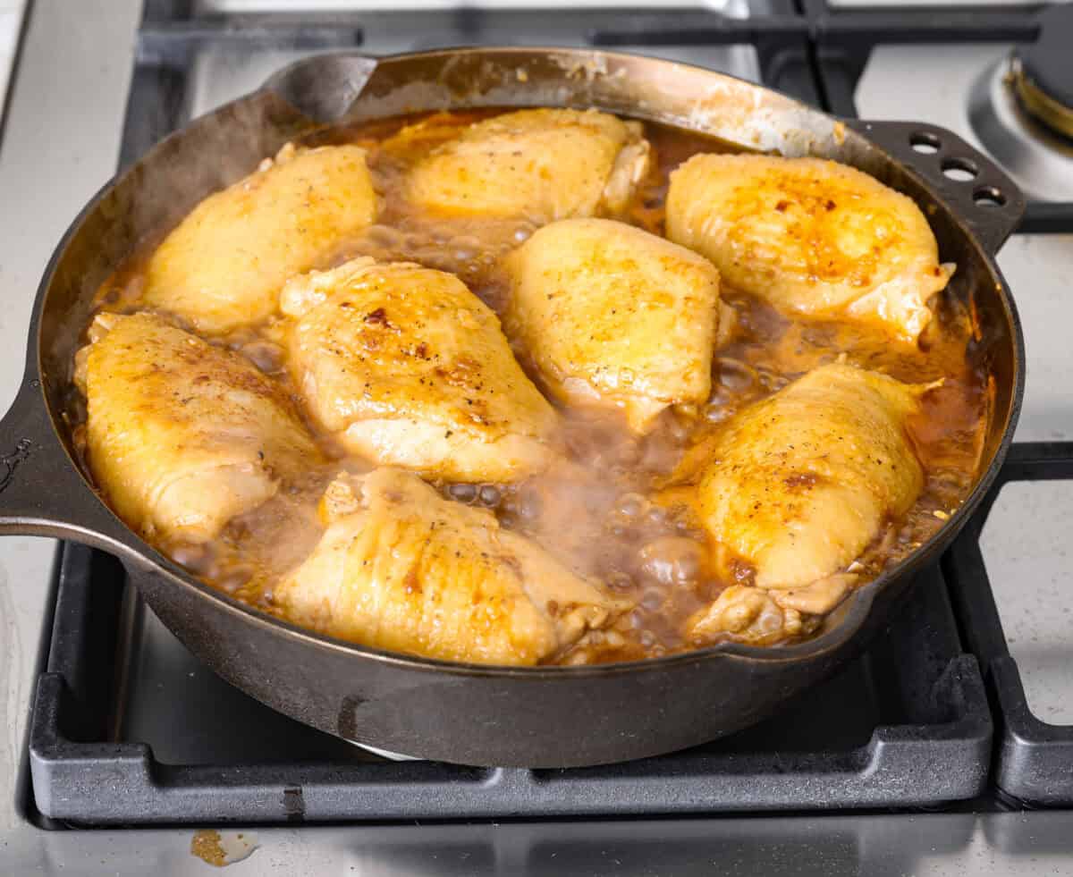 This incredibly tasty Coca-Cola chicken thigh recipe can be on the table in 40 minutes. The succulent sauce is a combination of savory soy sauce, Worcestershire, garlic, ketchup, and, of course, Coca-Cola. You've never had more flavorful chicken thighs than these! Angle shot of coca-cola chicken cooking in the skillet.