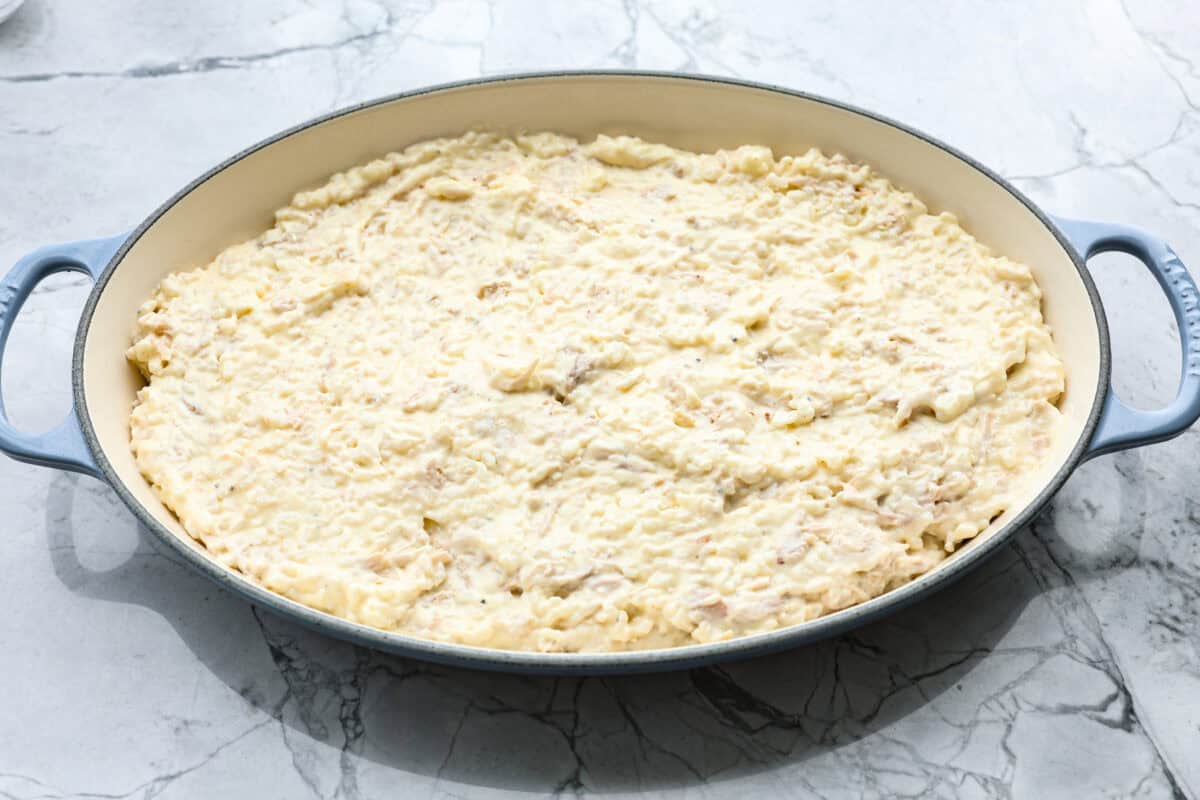 Angel Chicken and Rice Casserole is a creamy, cheesy, comforting classic. Tender chicken is folded into fluffy rice smothered in a savory cream sauce. The top has the most perfectly toasty cheesy crunch. You're going to love it! Overhead shot of the rice and cream sauce mixture in the bottom of a baking dish.