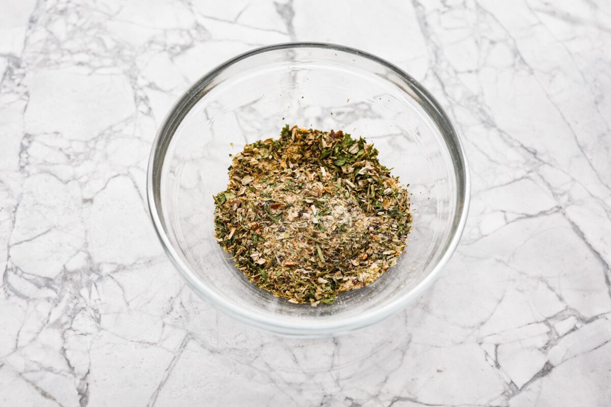 Homemade garlic herb seasoning is a great mix to have on hand. It has multiple uses, is full of flavor, and is adjustable to suit your taste preferences. It has the perfect mix of herbaceous dried herbs, garlic, onion powder, salt, and fresh cracked pepper. Overhead shot of the herbs and spices mixed in a bowl.