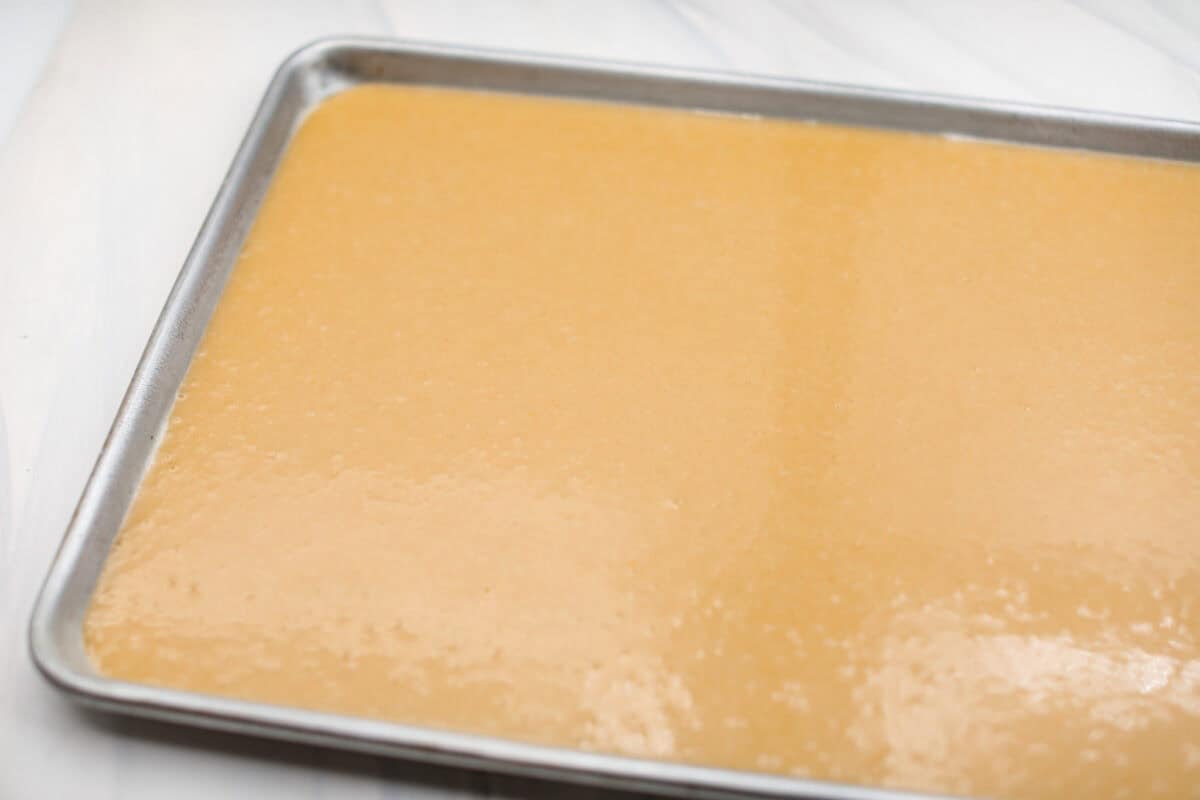 Browned Butter Sheet Cake is the perfect blend of moist, sweet, and irresistibly nutty. With the rich, caramel-like flavor of browned butter baked into every bite, this cake is a treat for anyone who loves a touch of warmth in their desserts. Angle shot of the cake batter spread evenly in the baking sheet.