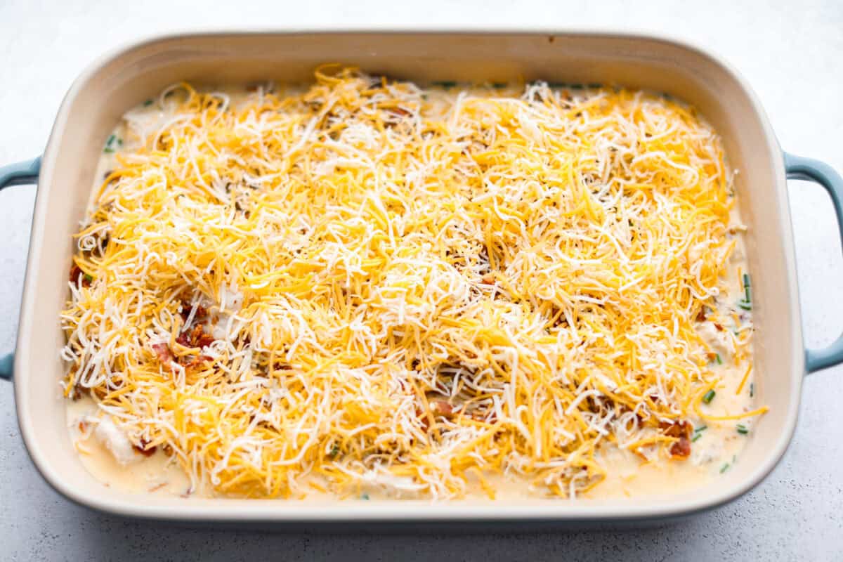 This bubble up breakfast casserole is simple to prepare and super flavorful! It's made with layers of biscuit, crispy bacon, savory sausage, fluffy eggs and melty cheese. Everyone will get out of bed and run to the breakfast table for this yummy dish! Overhead shot of egg, meat and biscuits covered with cheese ready to go in the oven.