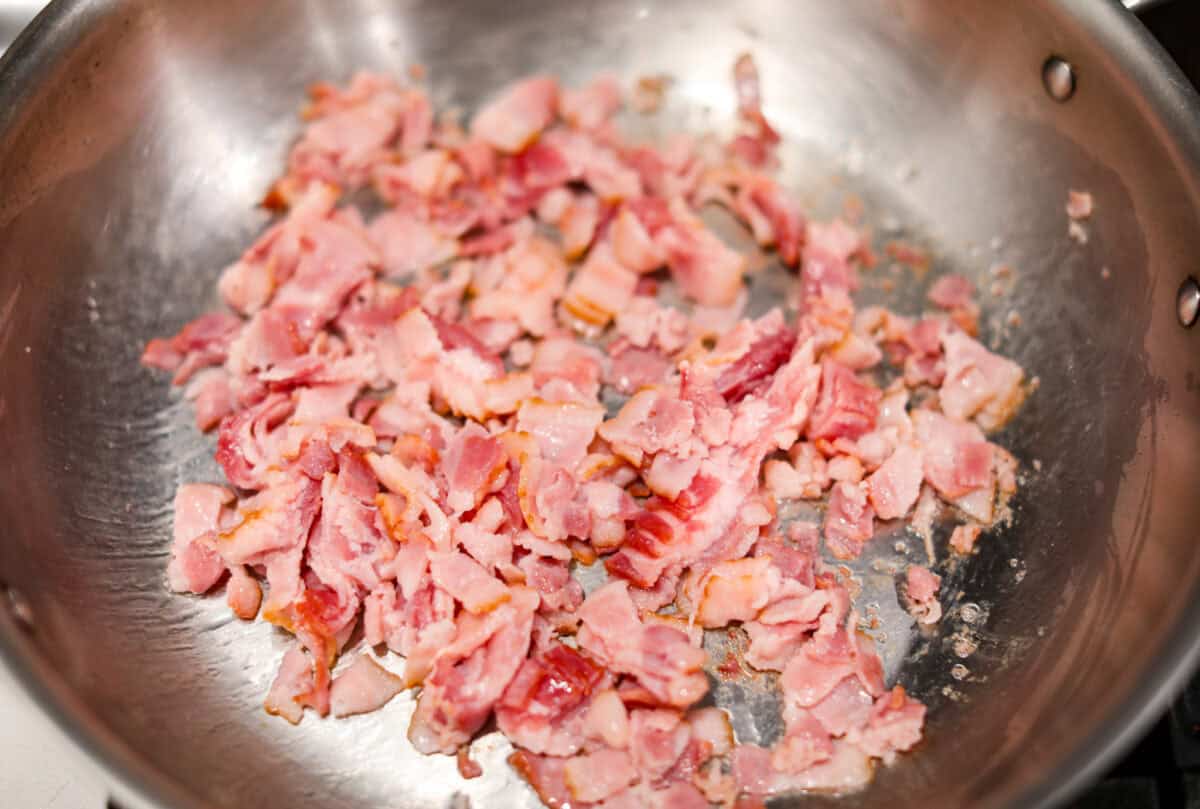 This bubble up breakfast casserole is simple to prepare and super flavorful! It's made with layers of biscuit, crispy bacon, savory sausage, fluffy eggs and melty cheese. Everyone will get out of bed and run to the breakfast table for this yummy dish! Overhead shot of bacon being cooked in a skillet.